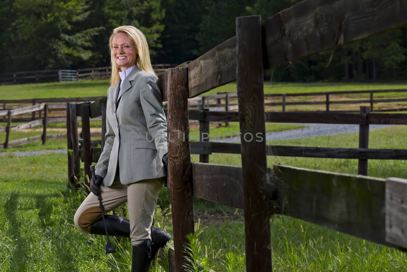 A blonde equestrian model poses outdoors before a horse show