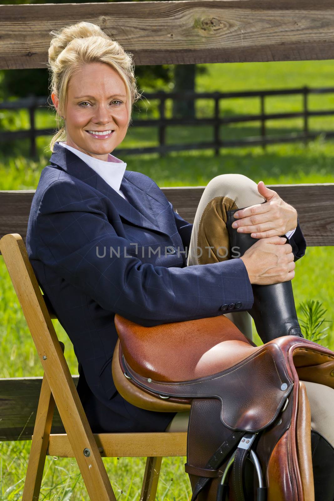 A blonde equestrian model poses outdoors before a horse show