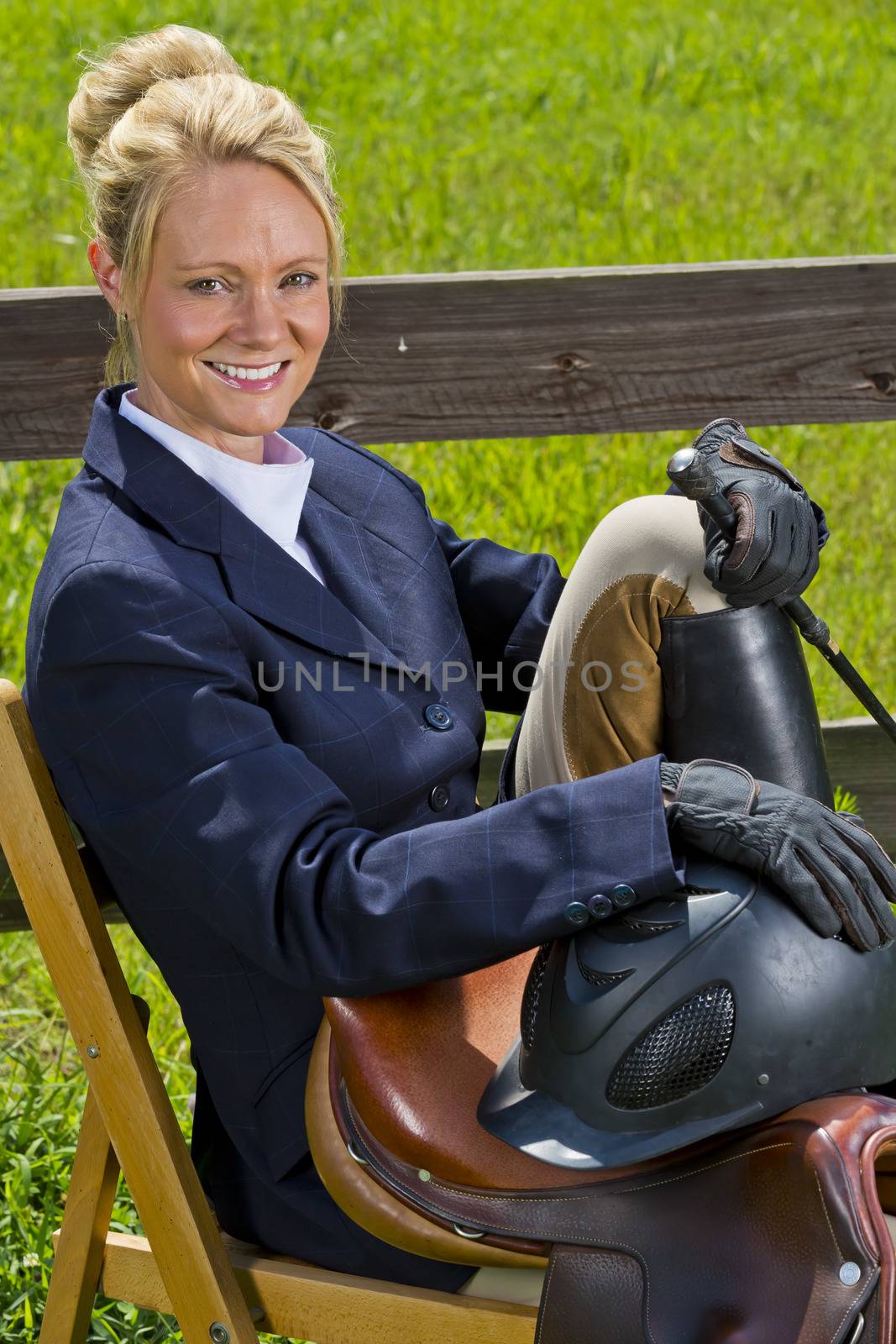 A blonde equestrian model poses outdoors before a horse show