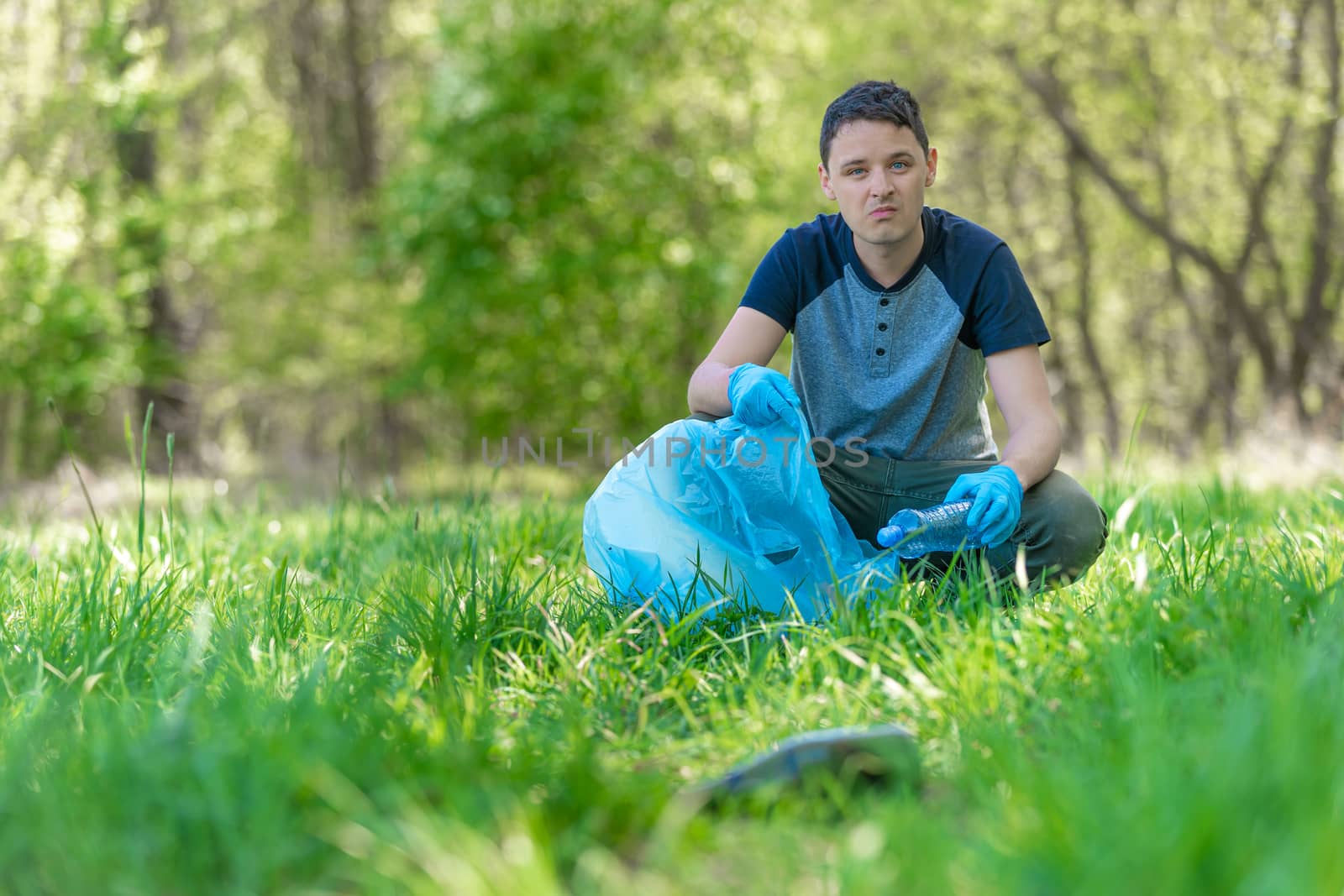 The volunteer cleans the forest from garbage, protects the environment.