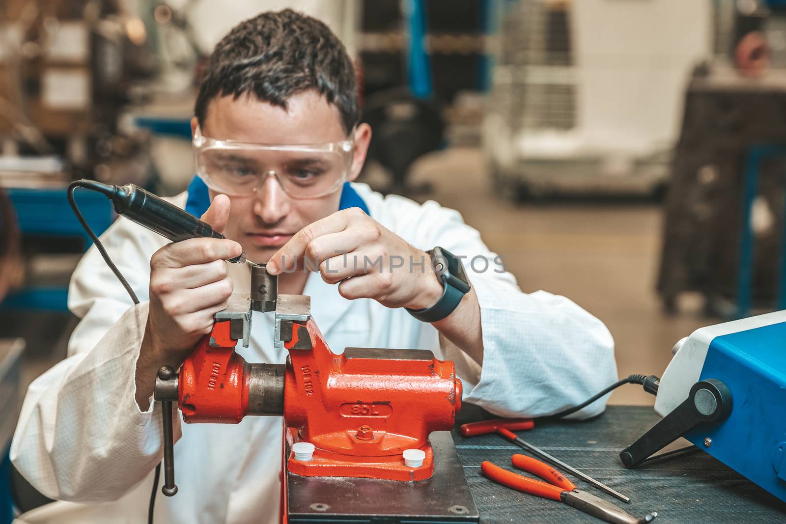 student of technical school on practical exam when working with vise and electric grinder.