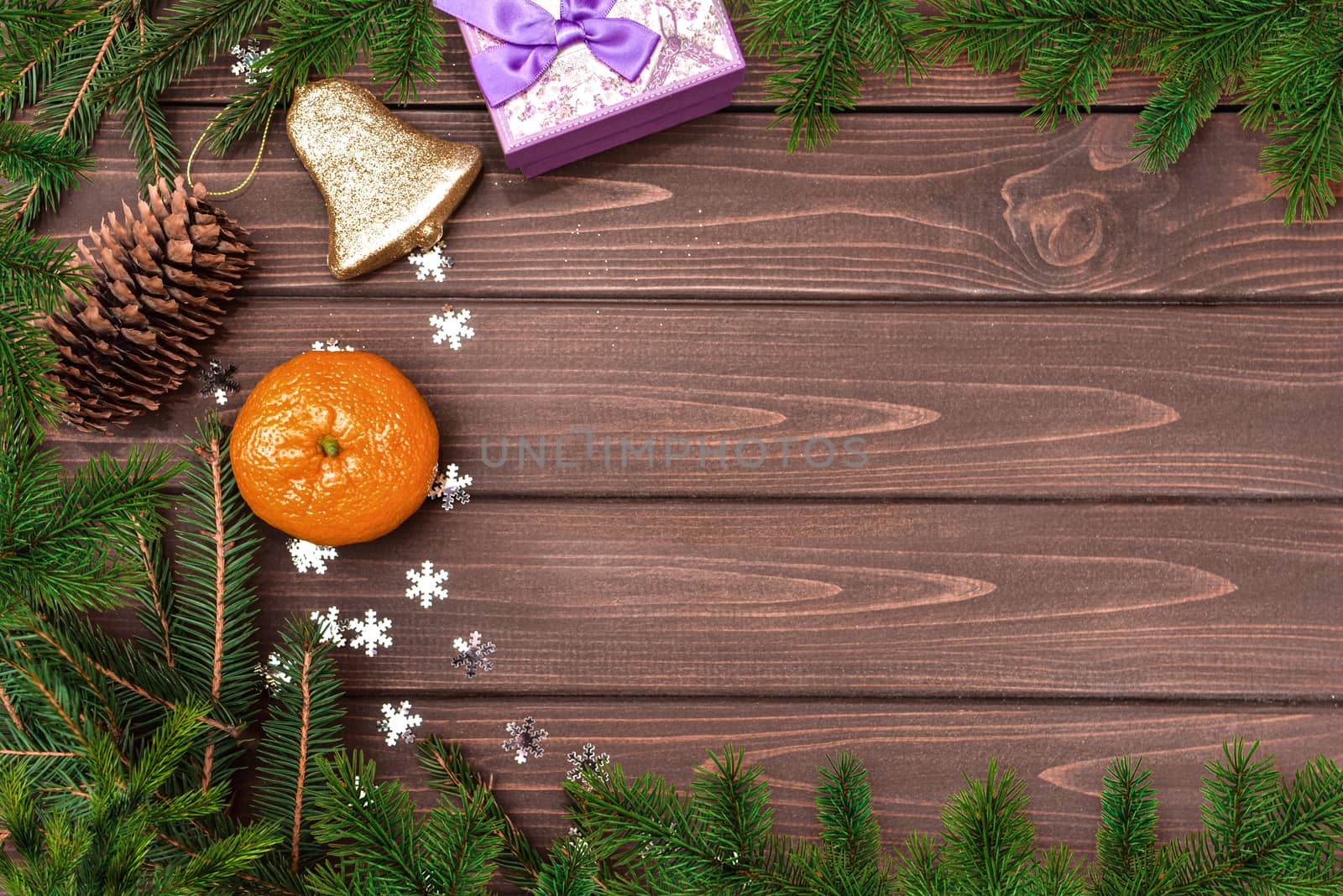 Christmas background, Fir branch, cones , orange, bell and gifts on a wooden table. Space for text. View from above. Christmas atmosphere