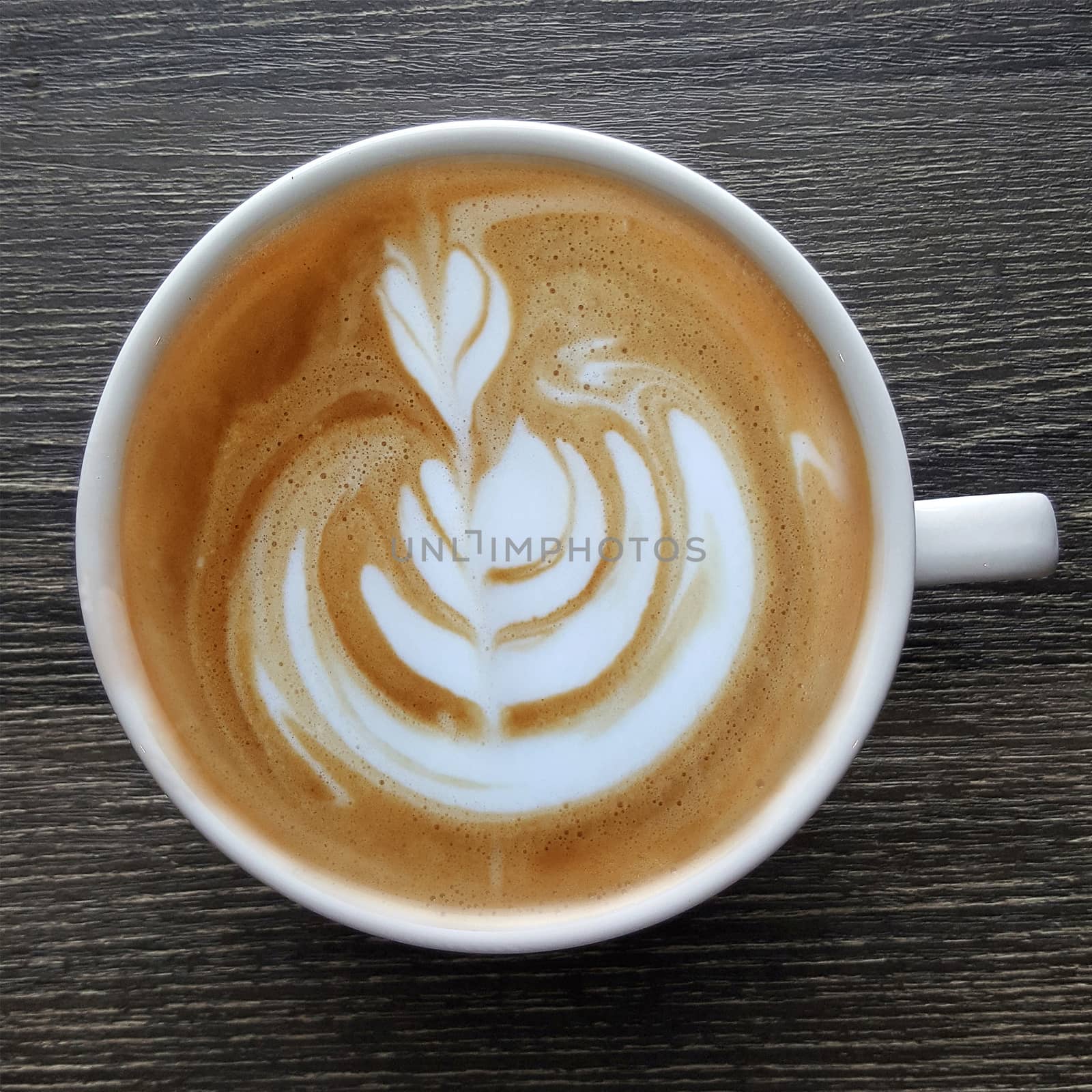 Top view of a mug of latte art coffee on timber background.