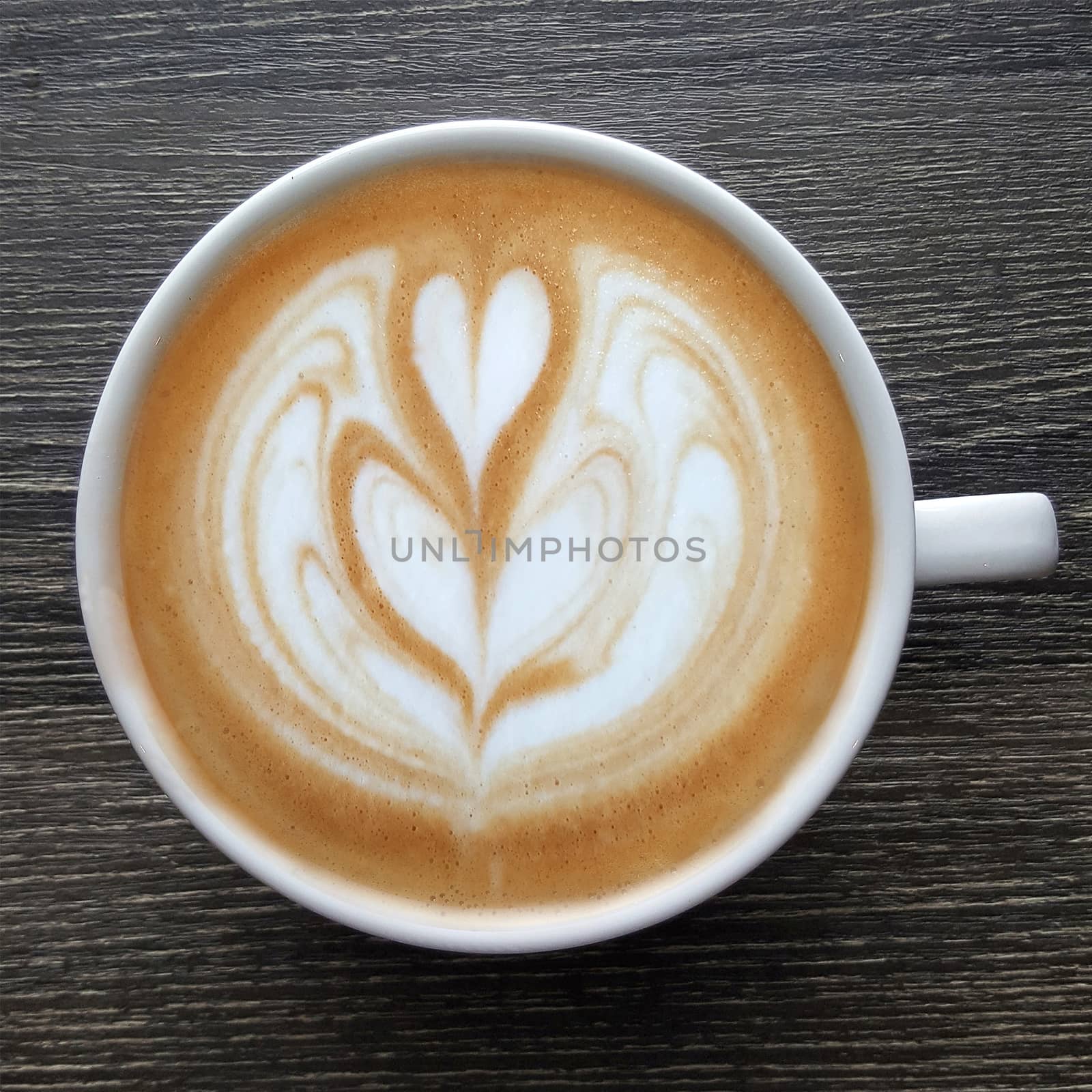 Top view of a mug of latte art coffee on timber background.