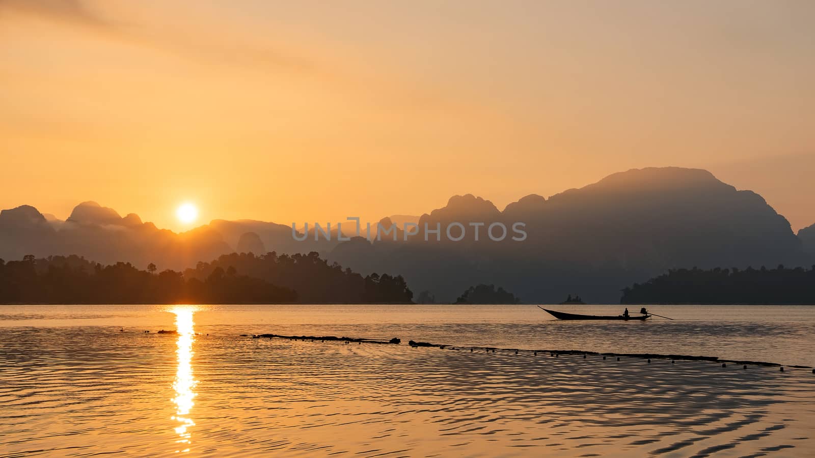 silhouette image of a  boat sailing in a dam in southern of Thailand in the morning.