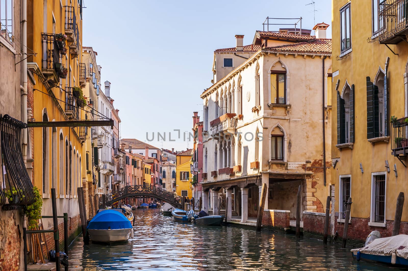 Canal and its colorful facades and boats in Venice in Veneto, Italy by Frederic