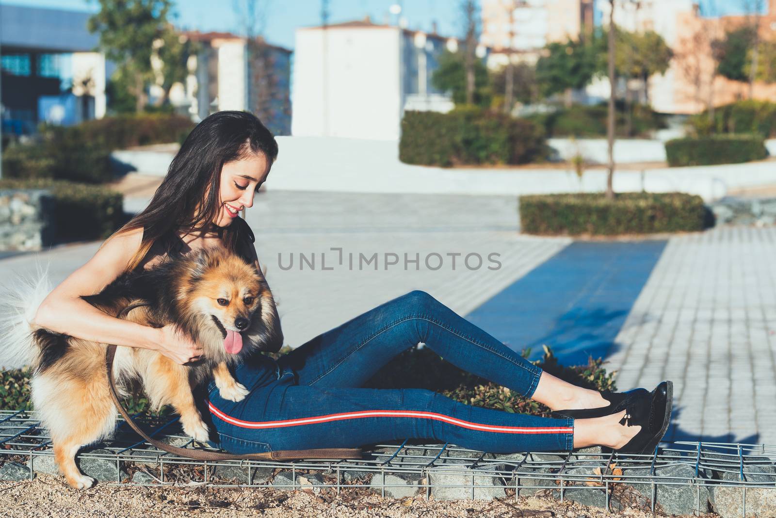 attractive young  woman sitting with dog in the city