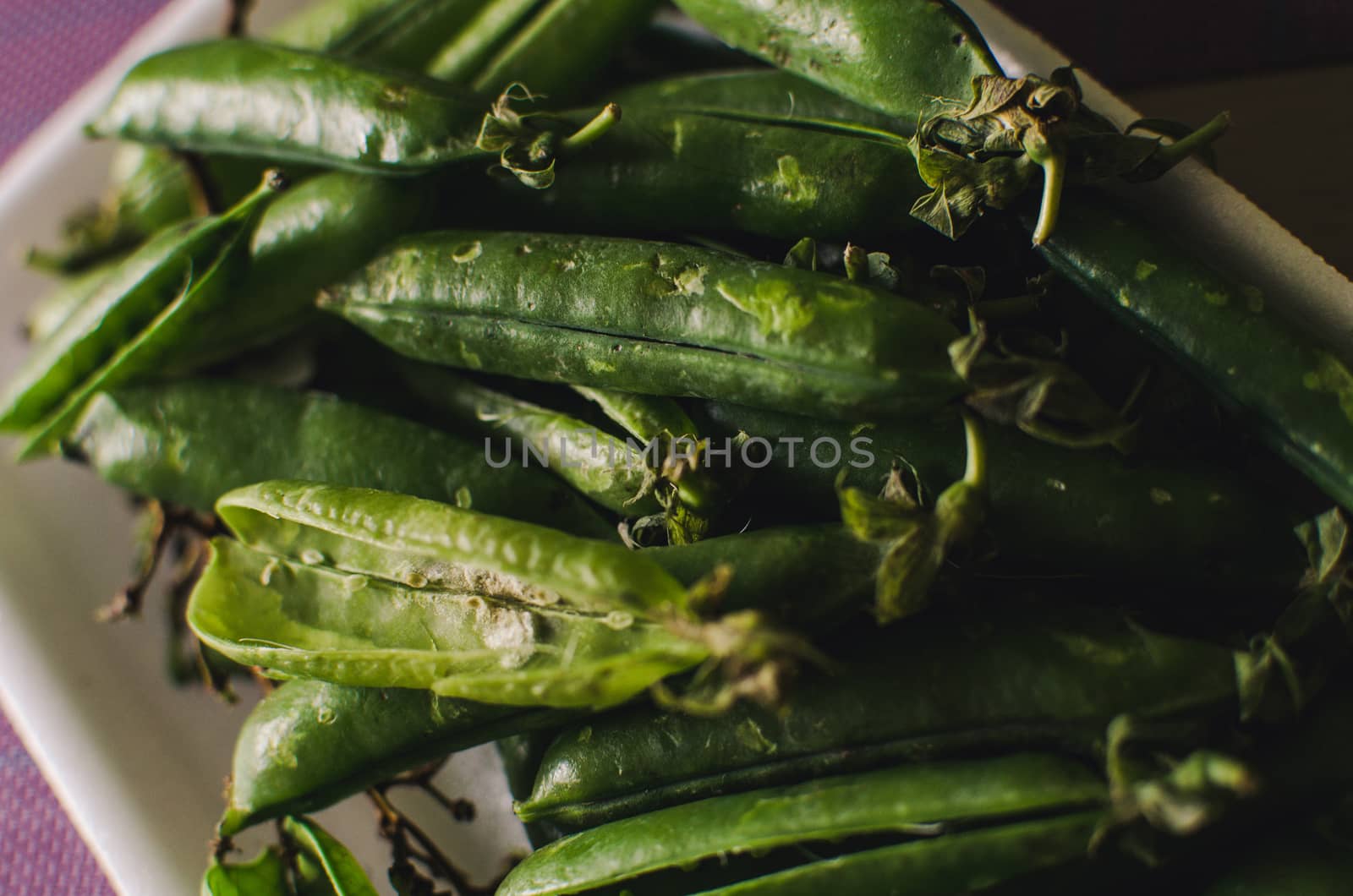 Many peas with their husks in a bowl