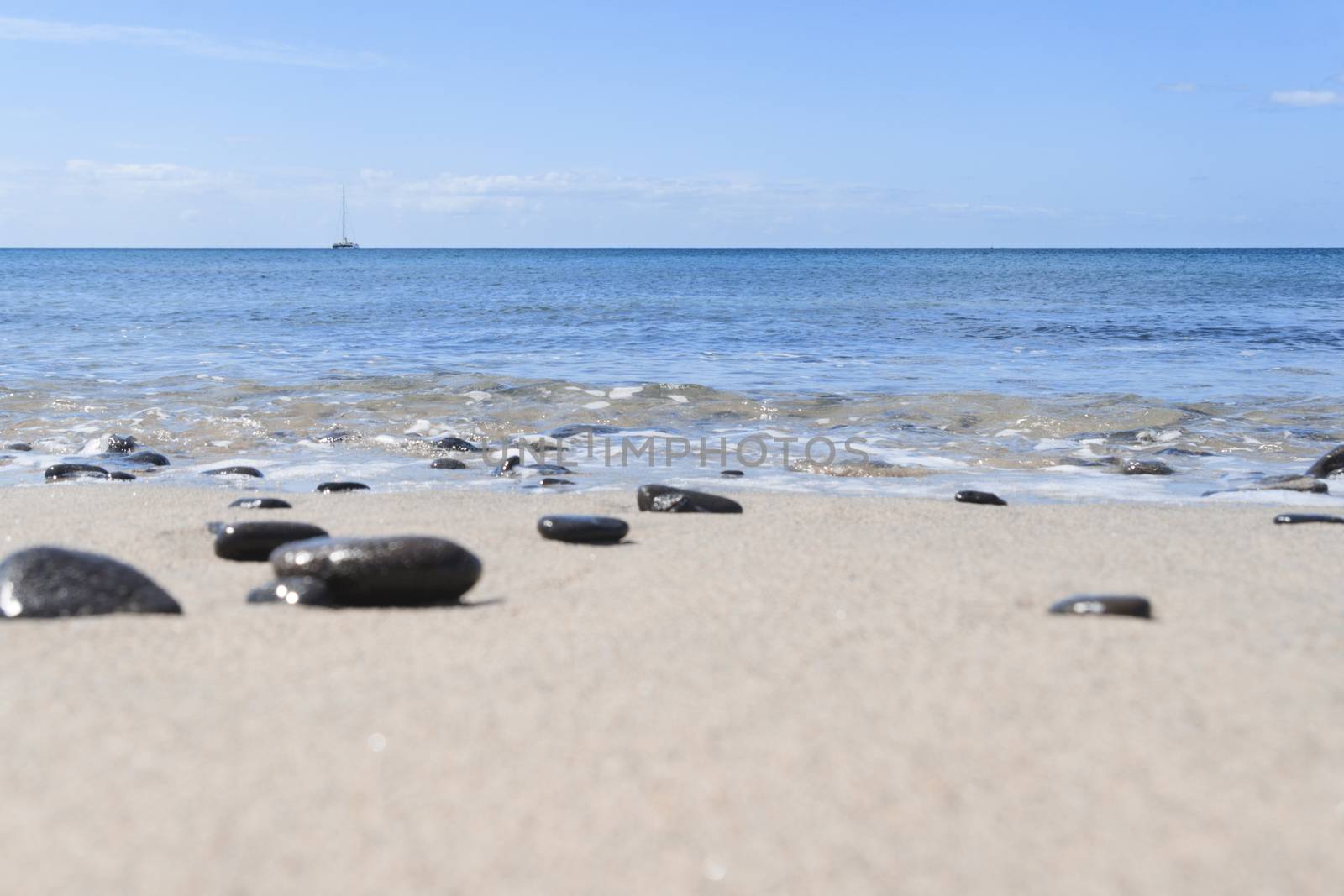 Dark stones, blue sky and wild beach in Fuerteventura island