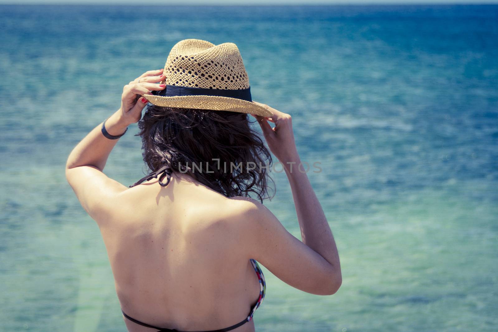 Beautiful woman in sunhat and bikini looking at the beach on a hot summer day. Photo from Fuerteventura Island, Spain by tanaonte