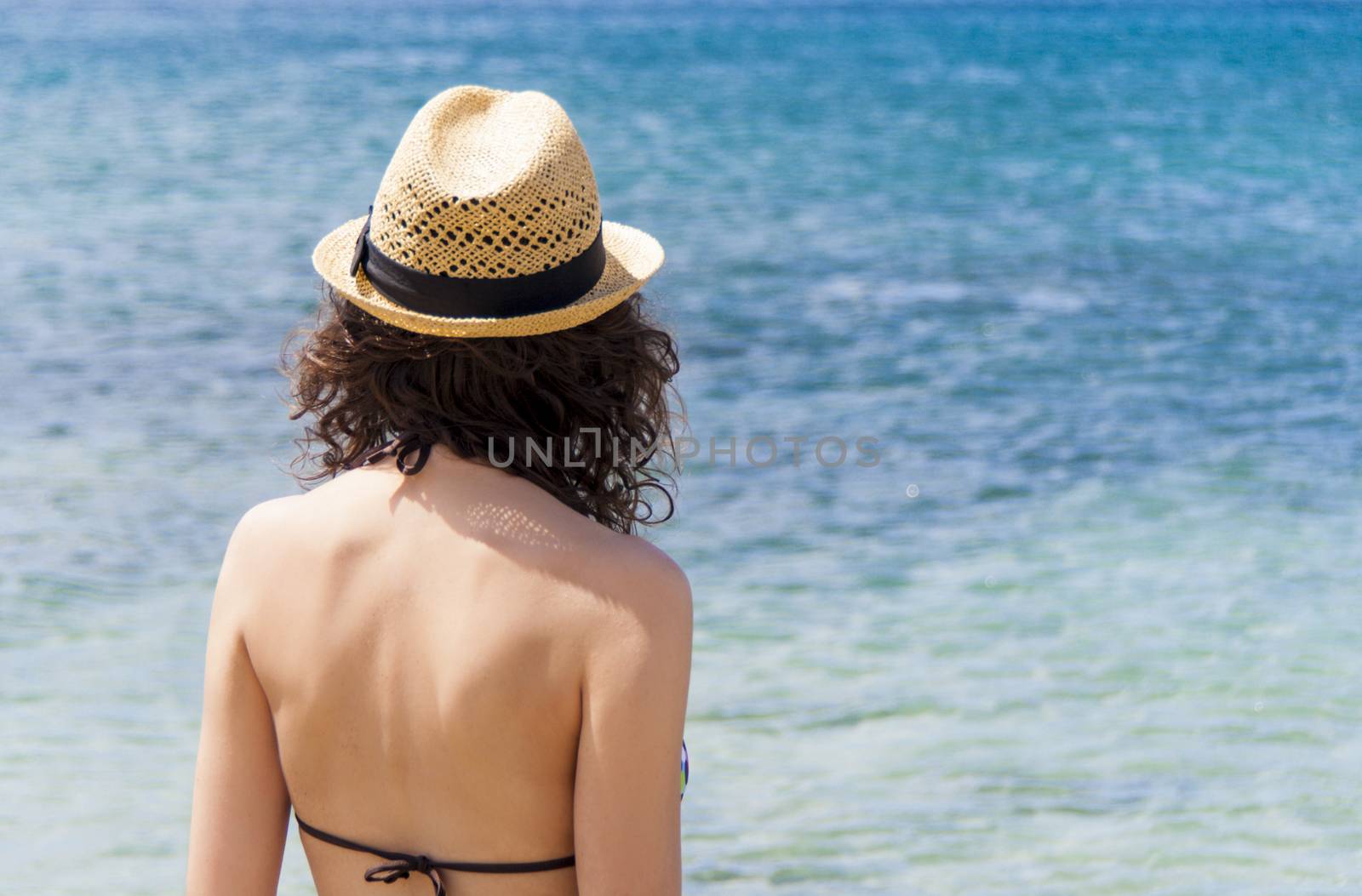 Beach vacation. Beautiful woman in sunhat and bikini looking view of beach ocean on hot summer day. Photo from Fuerteventura Island, Spain.