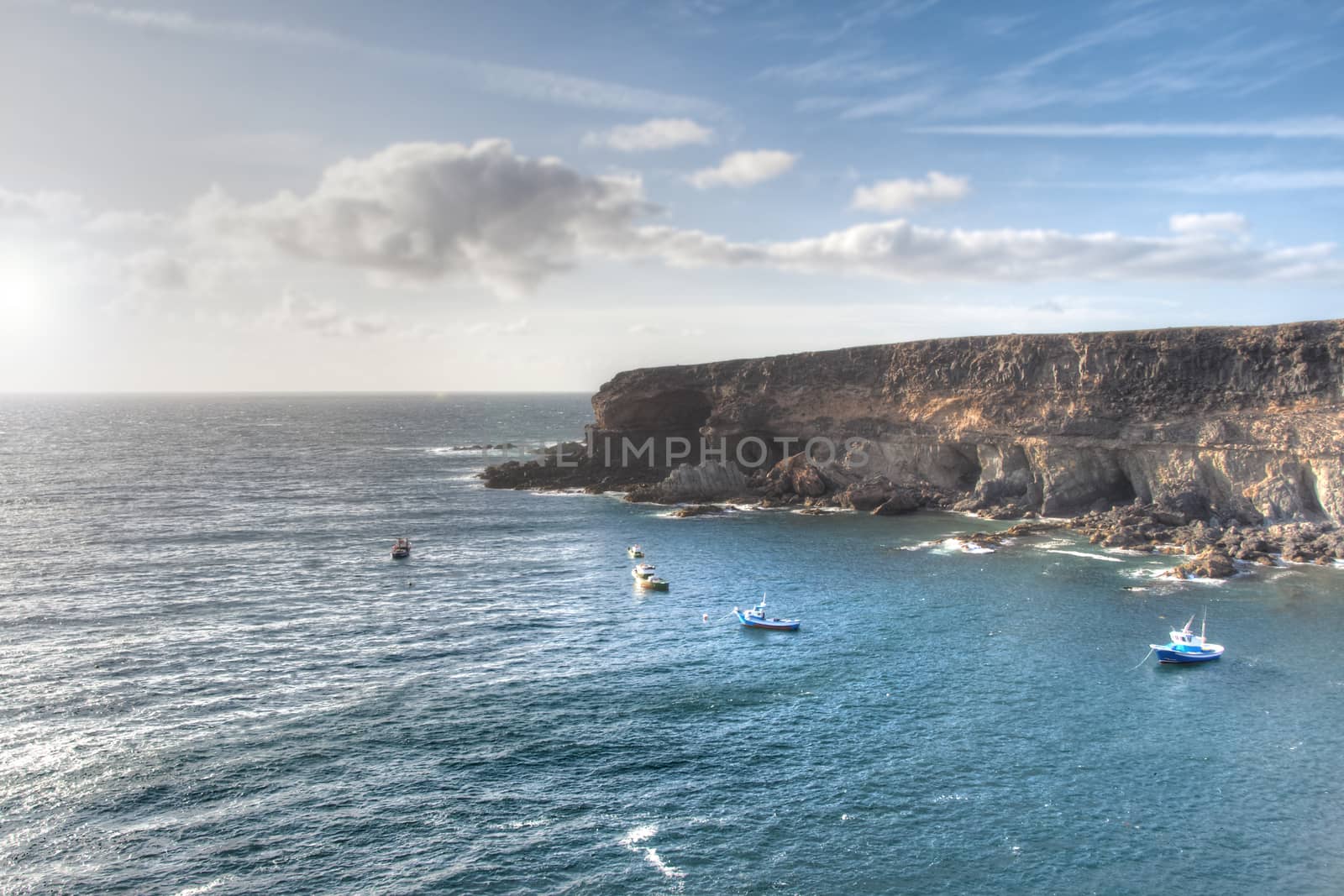 Panoramic view of a cliff at sunset , with several fishermen boats.