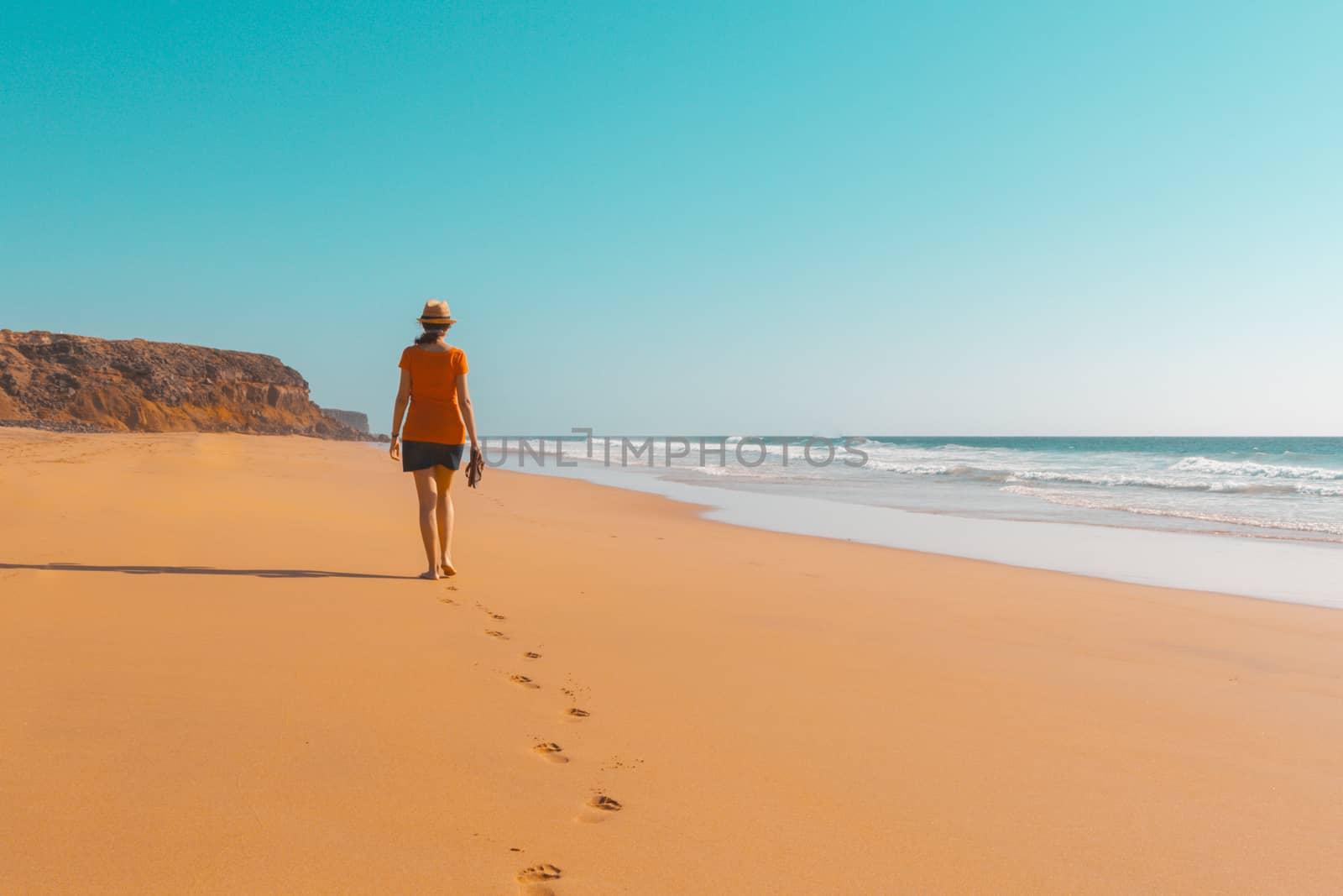 Teal and orange mood of Solitary girl walking on beach by tanaonte