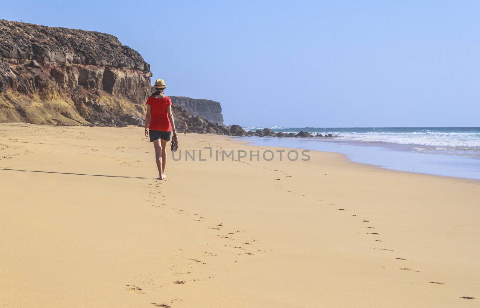 Lonely girl walking in a solitary beach. Image with many copy space available.