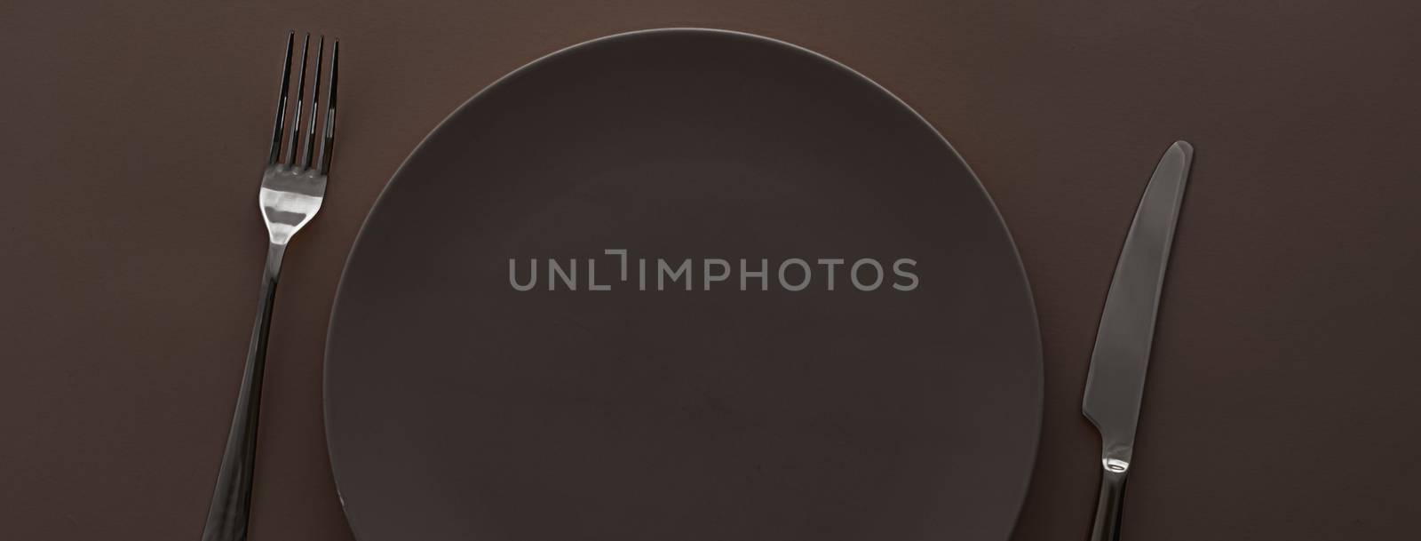 Empty plate and cutlery as mockup set on dark brown background, top tableware for chef table decor and menu branding by Anneleven