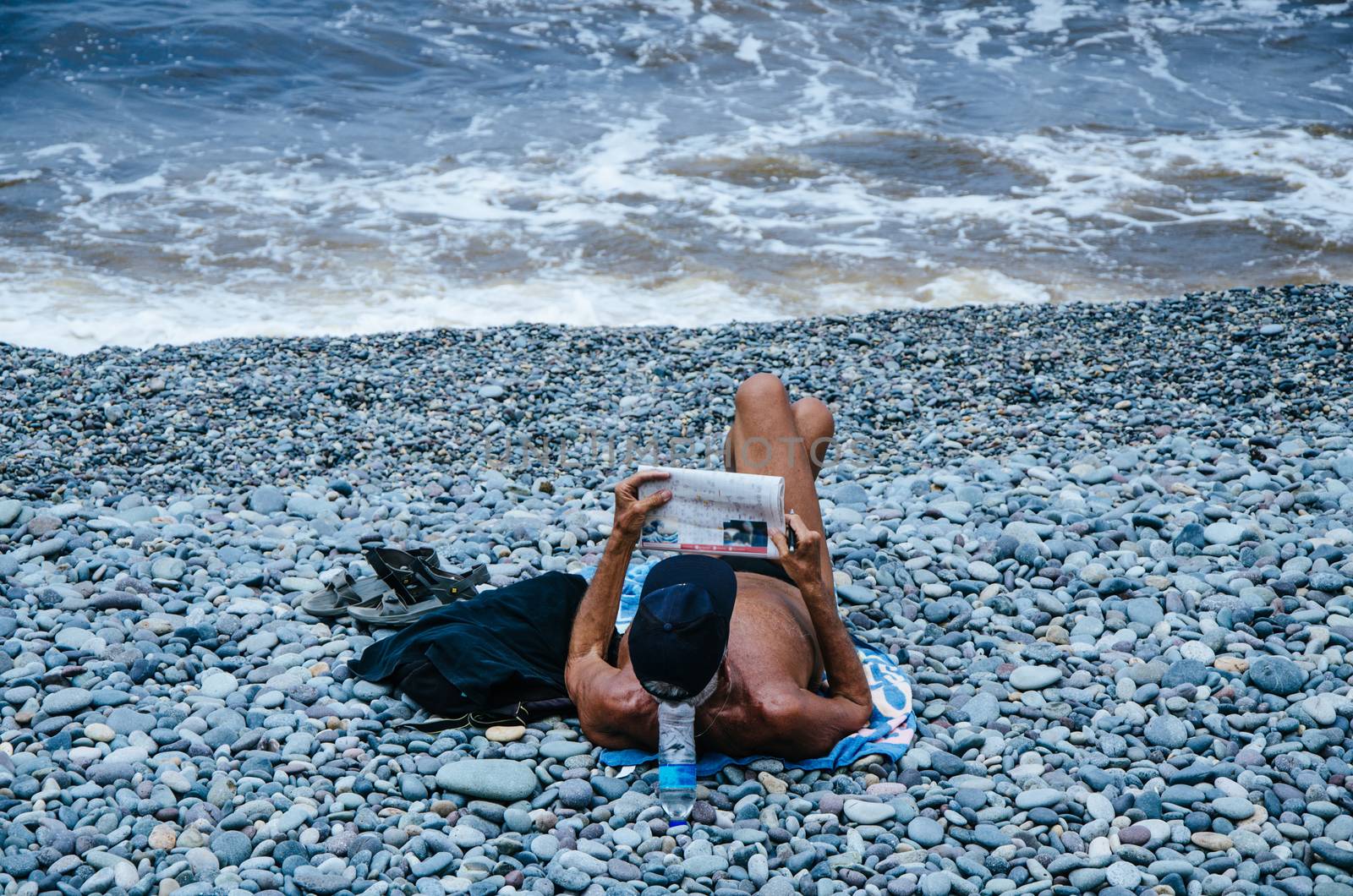 Man reading the newspaper on the beach and enjoying the summer