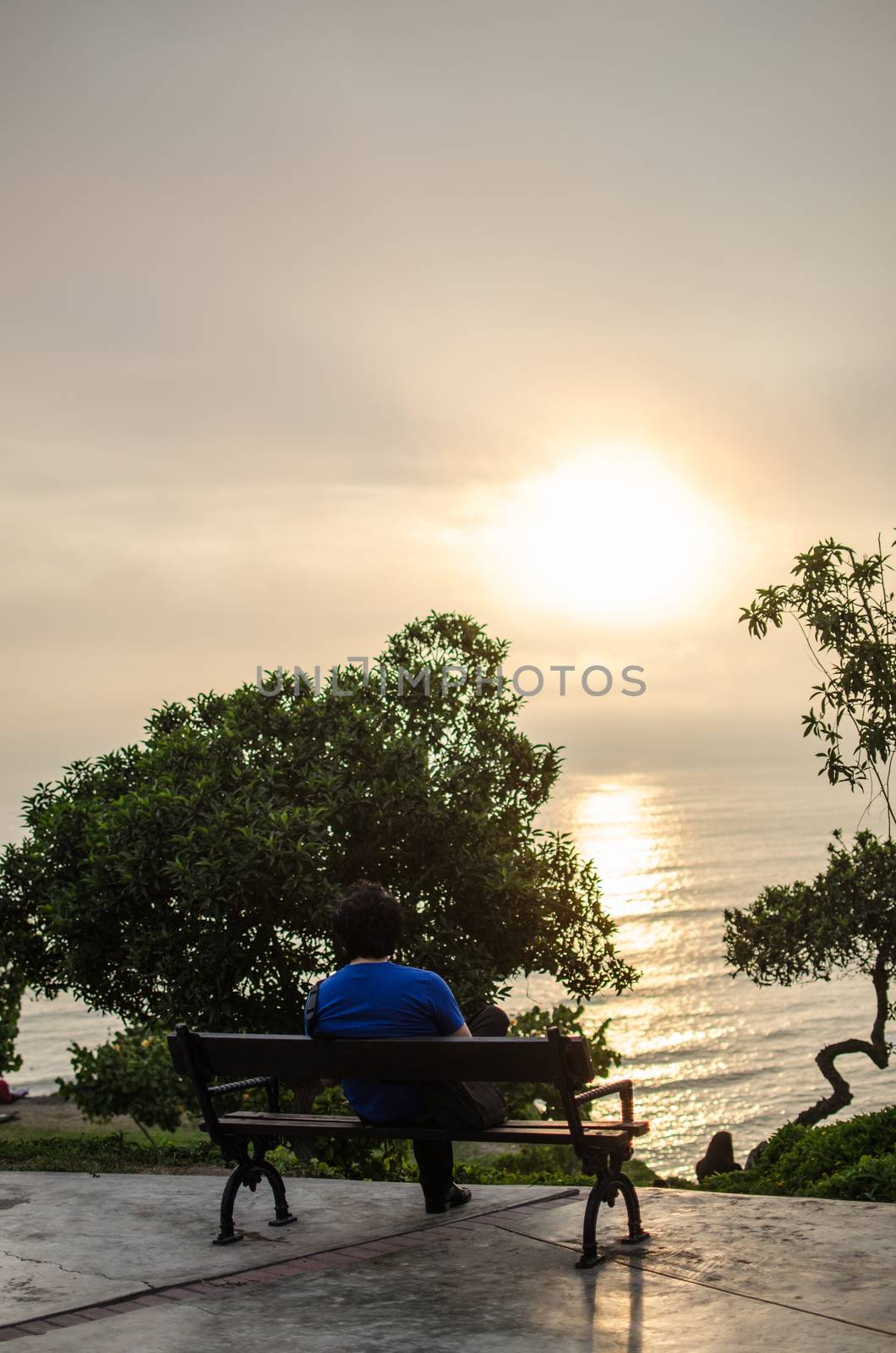 Man sitting in front of the sea watching the sunset