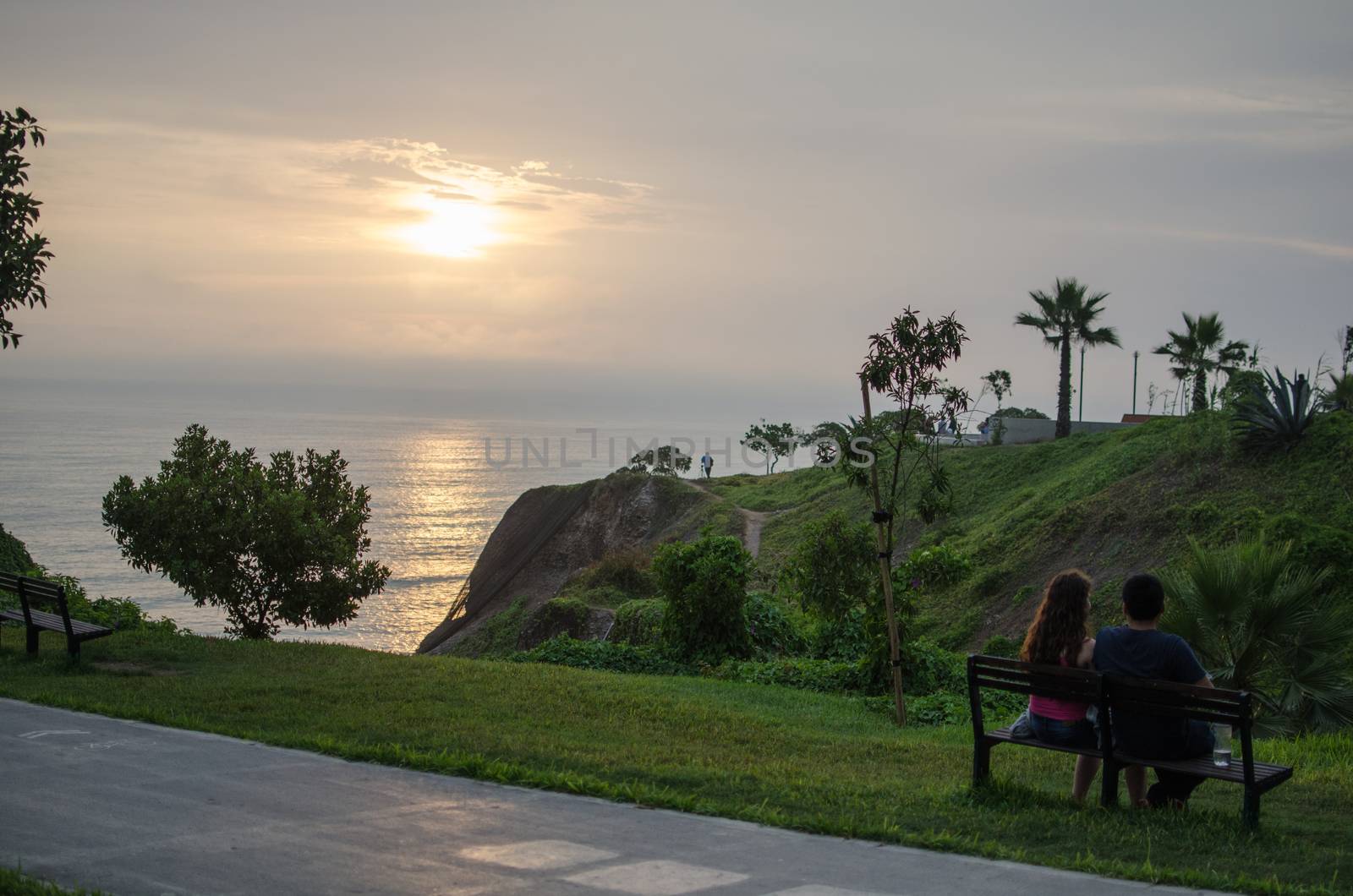 A couple sitting in front of the sea watching the sunset