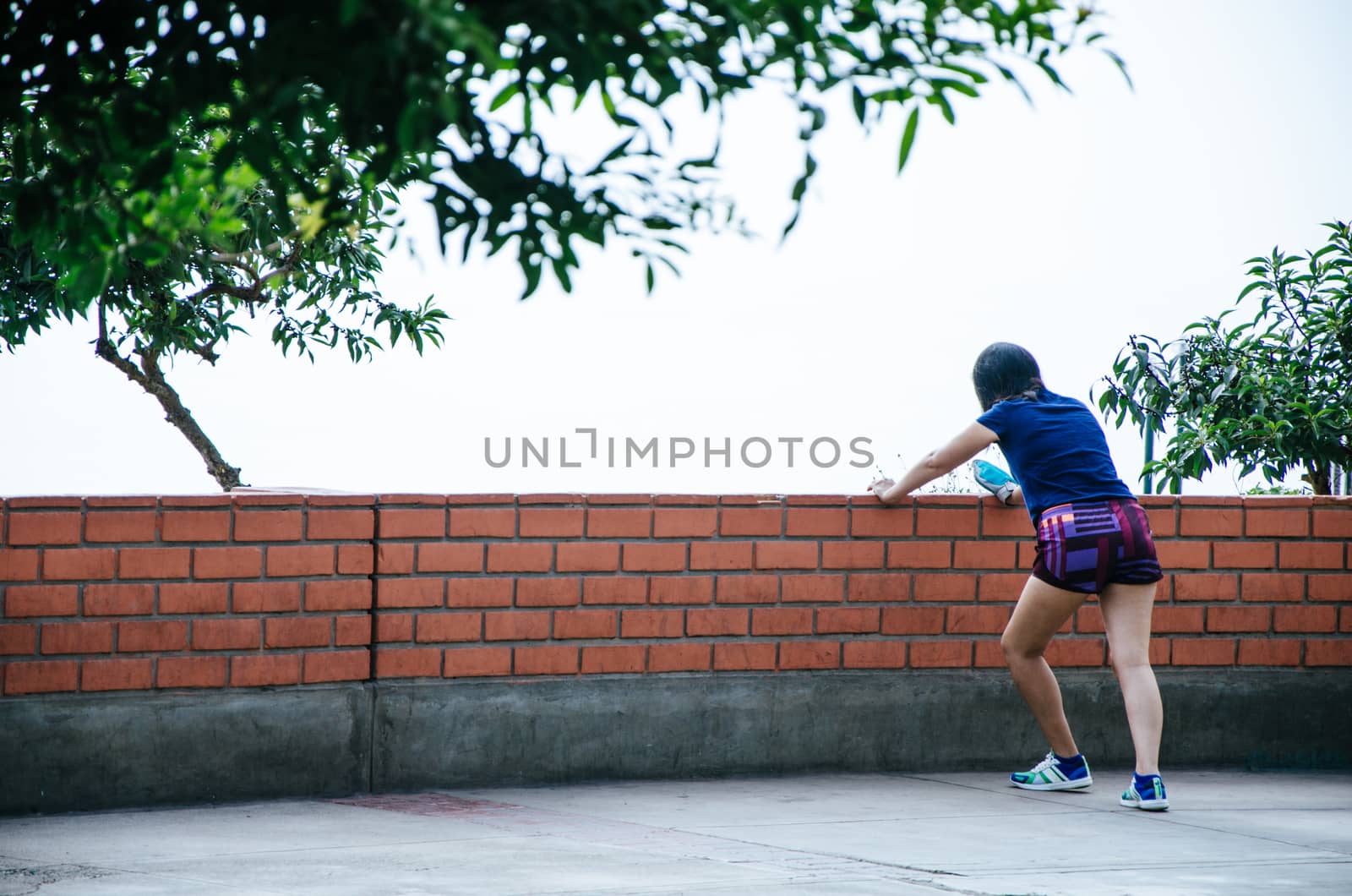 Woman lying on a wall doing exercises outdoors