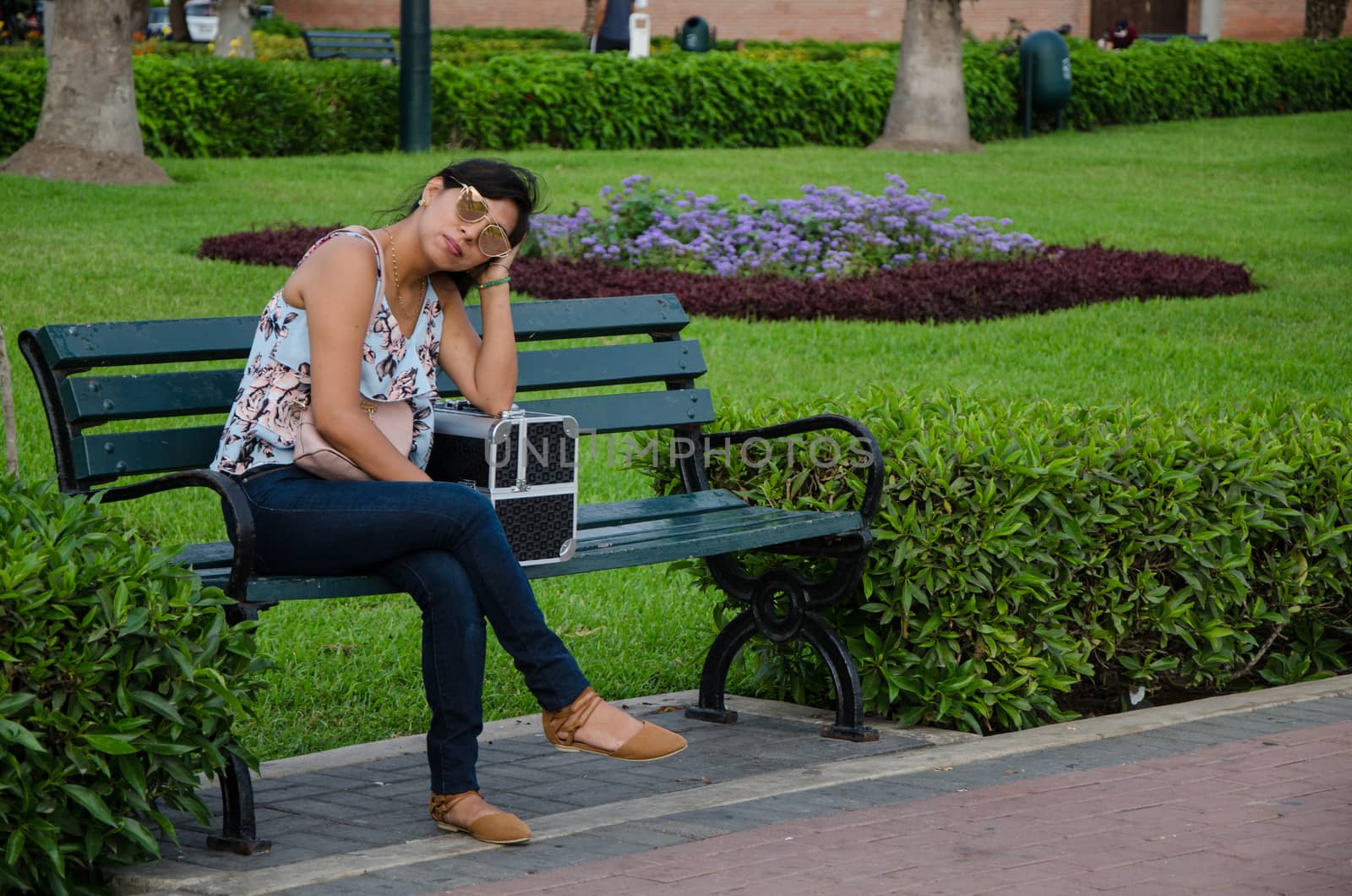 Girl with sunglasses on a park bench waiting