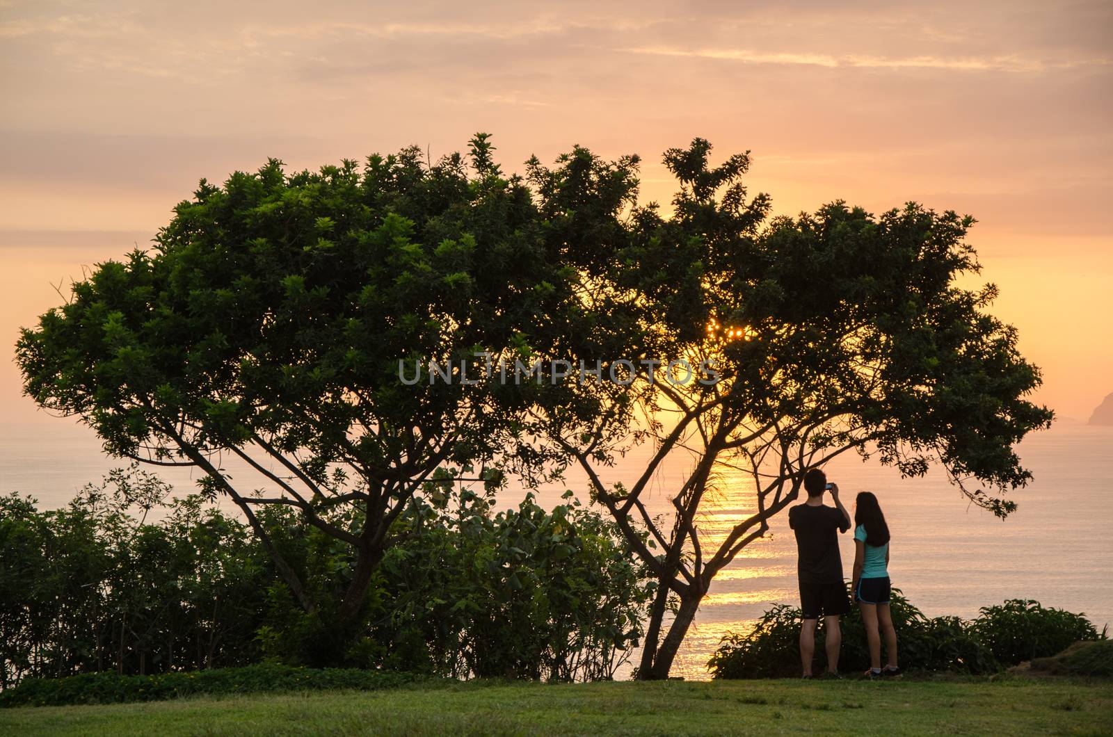 A couple taking pictures to the sea in the afternoon