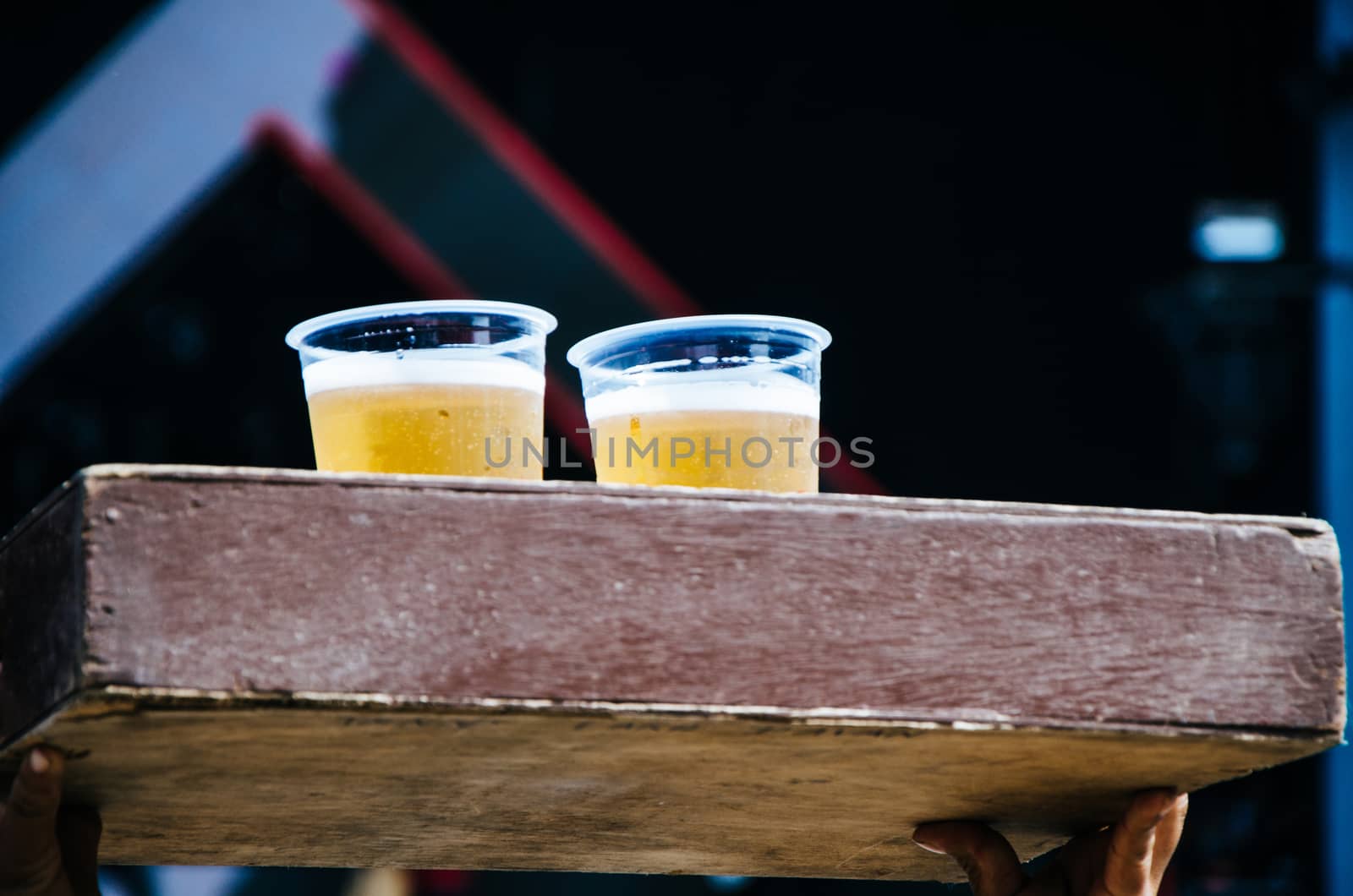 Two plastic cups with beer in a wooden box
