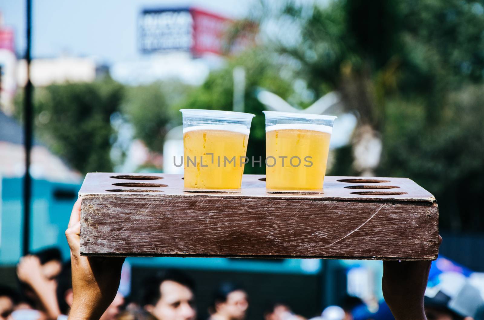 Two plastic cups with beer in a wooden box at a concert