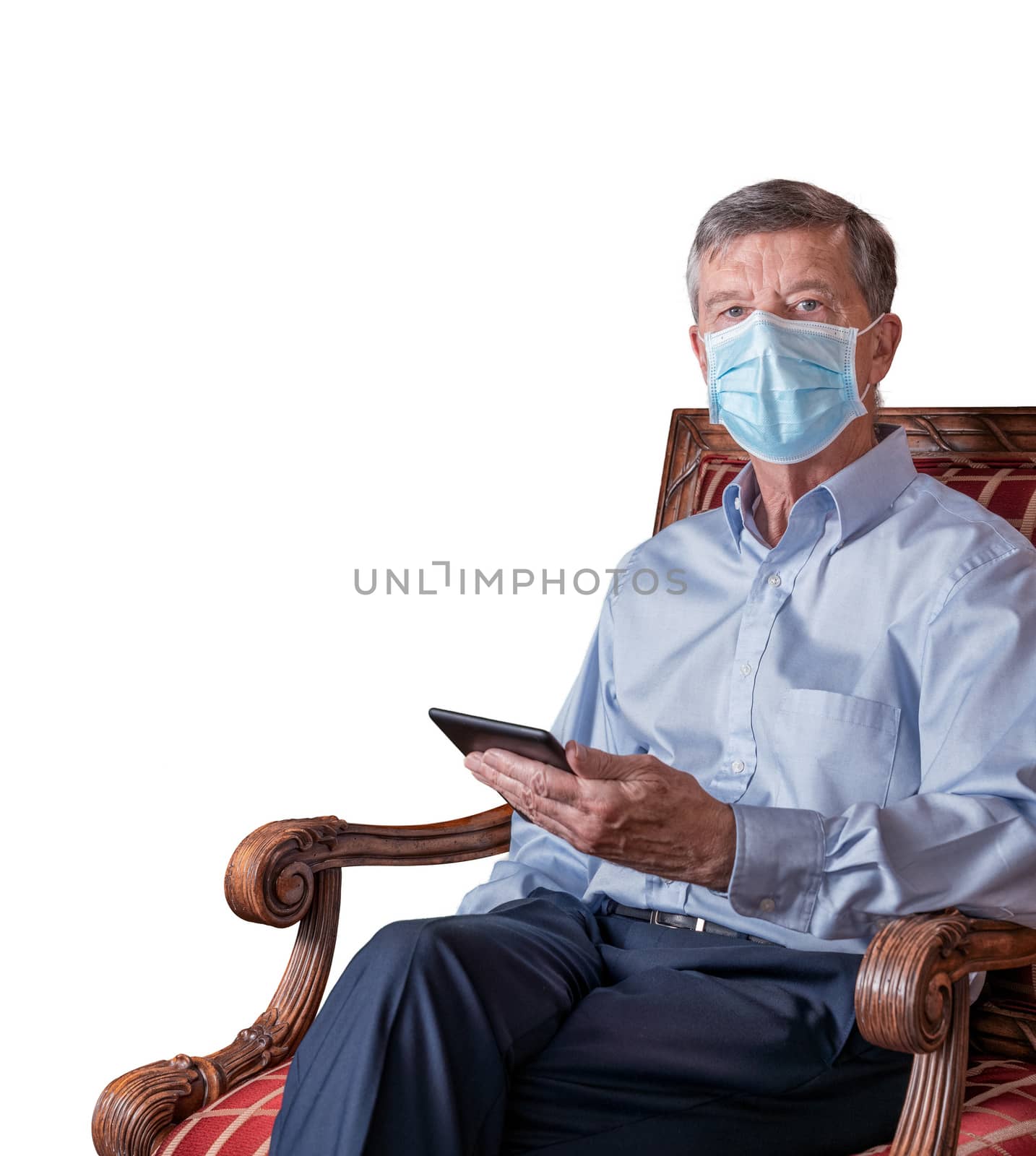 Senior man with face mask against virus reads an ebook tablet and isolated against white by steheap
