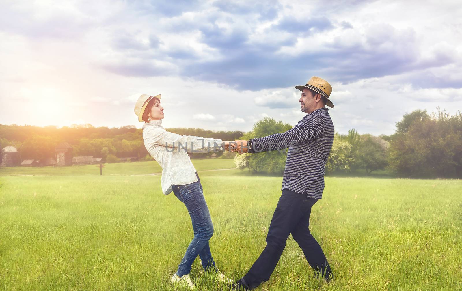 a portrait of a happy middle-aged couple holding hands in the field. by Nickstock