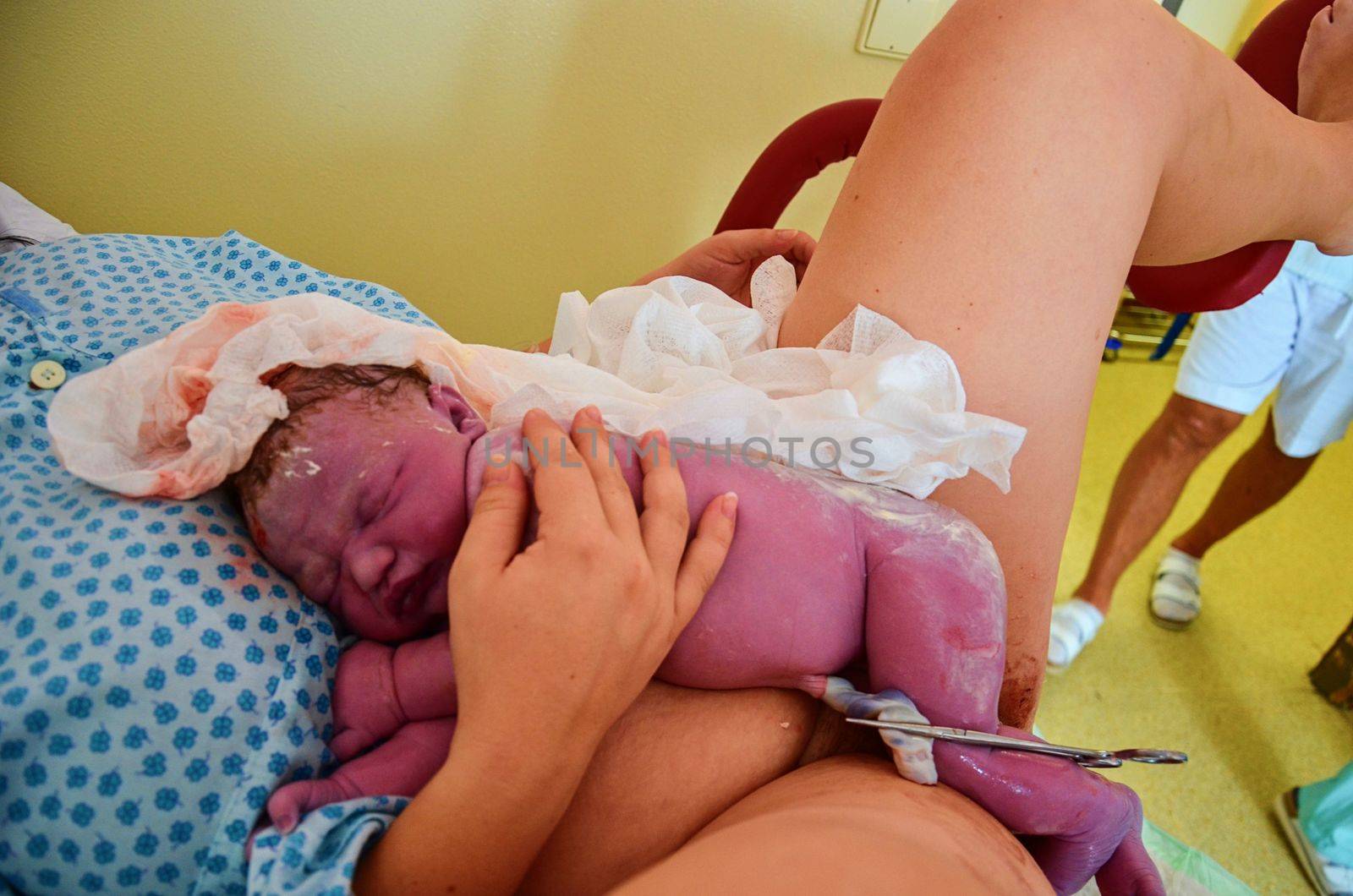 New born baby with umbilical cord after successful childbirth. Real birthing and new born baby in a hospital.