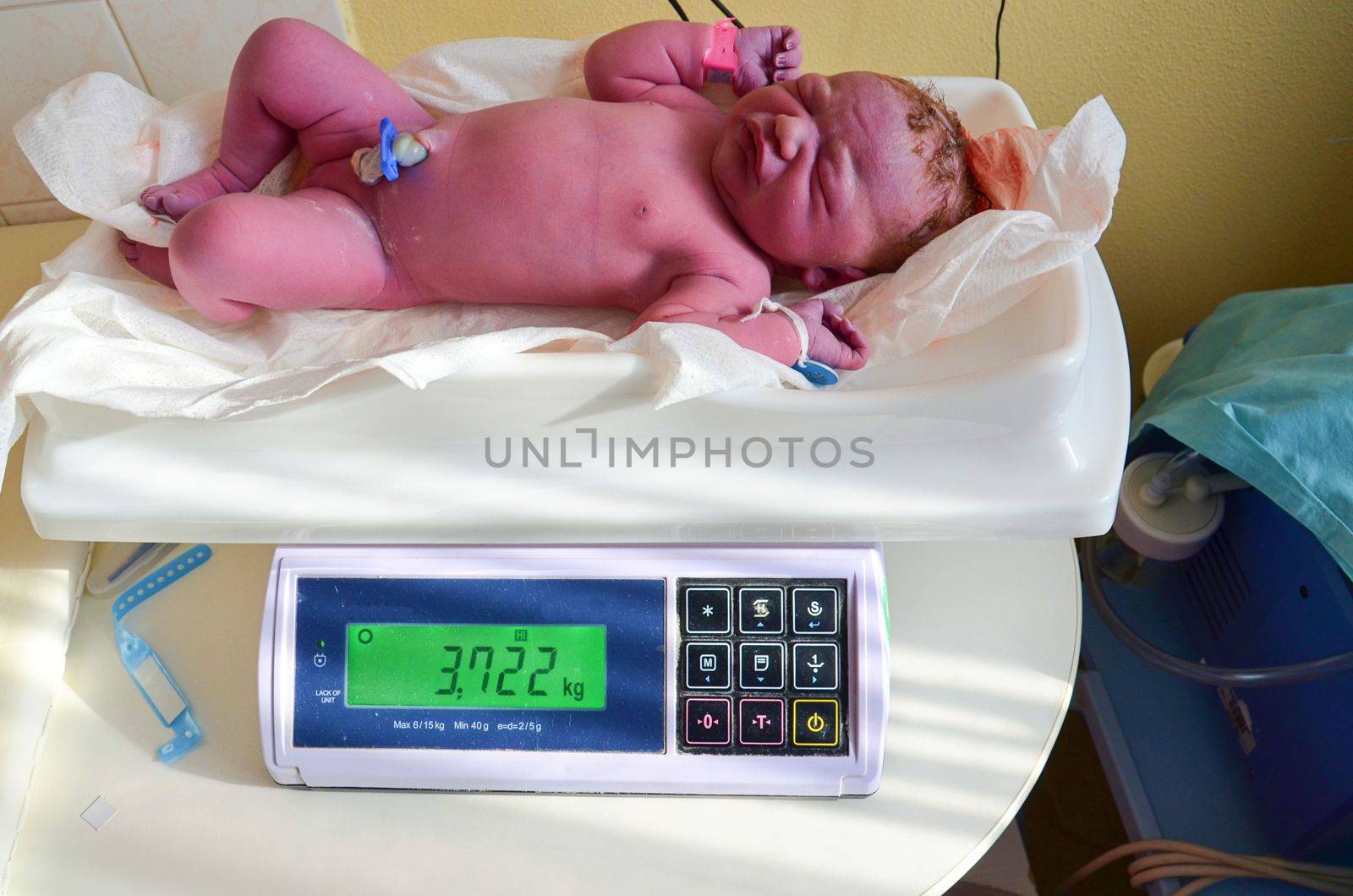 New born baby - girl with remainder of umbilical cord after successful childbirth. Real birthing and new born baby in a hospital. A healthy female newborn baby girl has been examined on the balance scale immediately after childbirth.