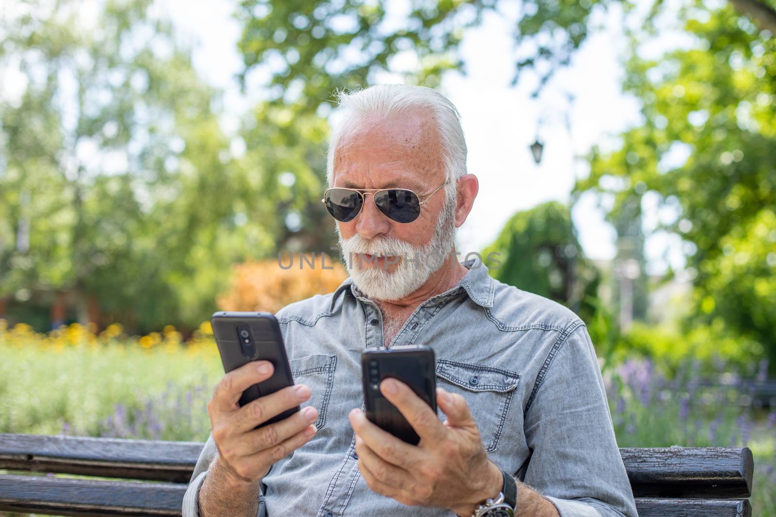 Old man compare two smartphones