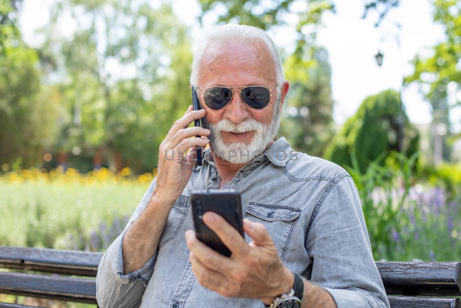 Old man compare two smartphones