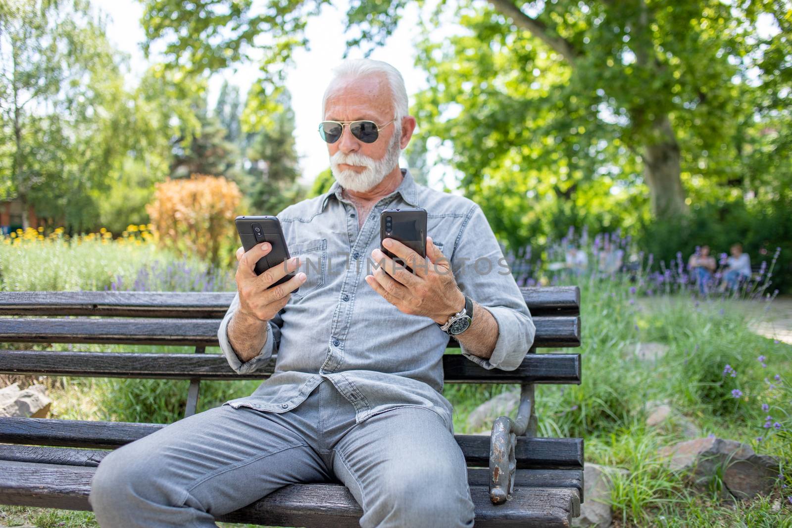 Old man compare two smartphones