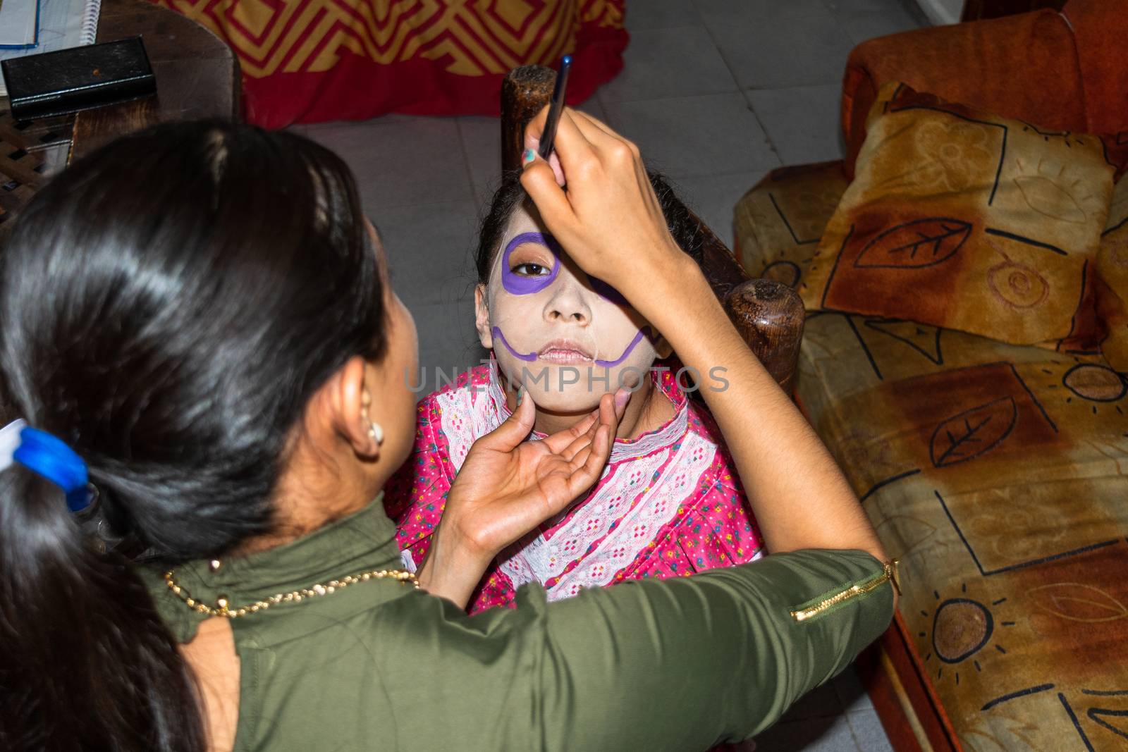 Young woman putting makeup of Catrina in a girl's face by Tonhio