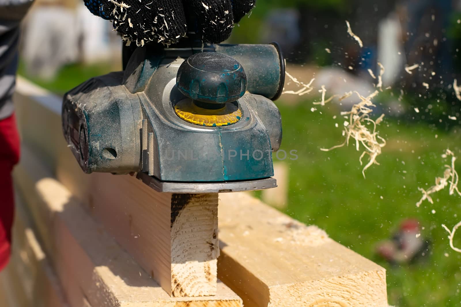 Construction, wood processing. Worker, man planing boards with electric tools, chips flying in all directions