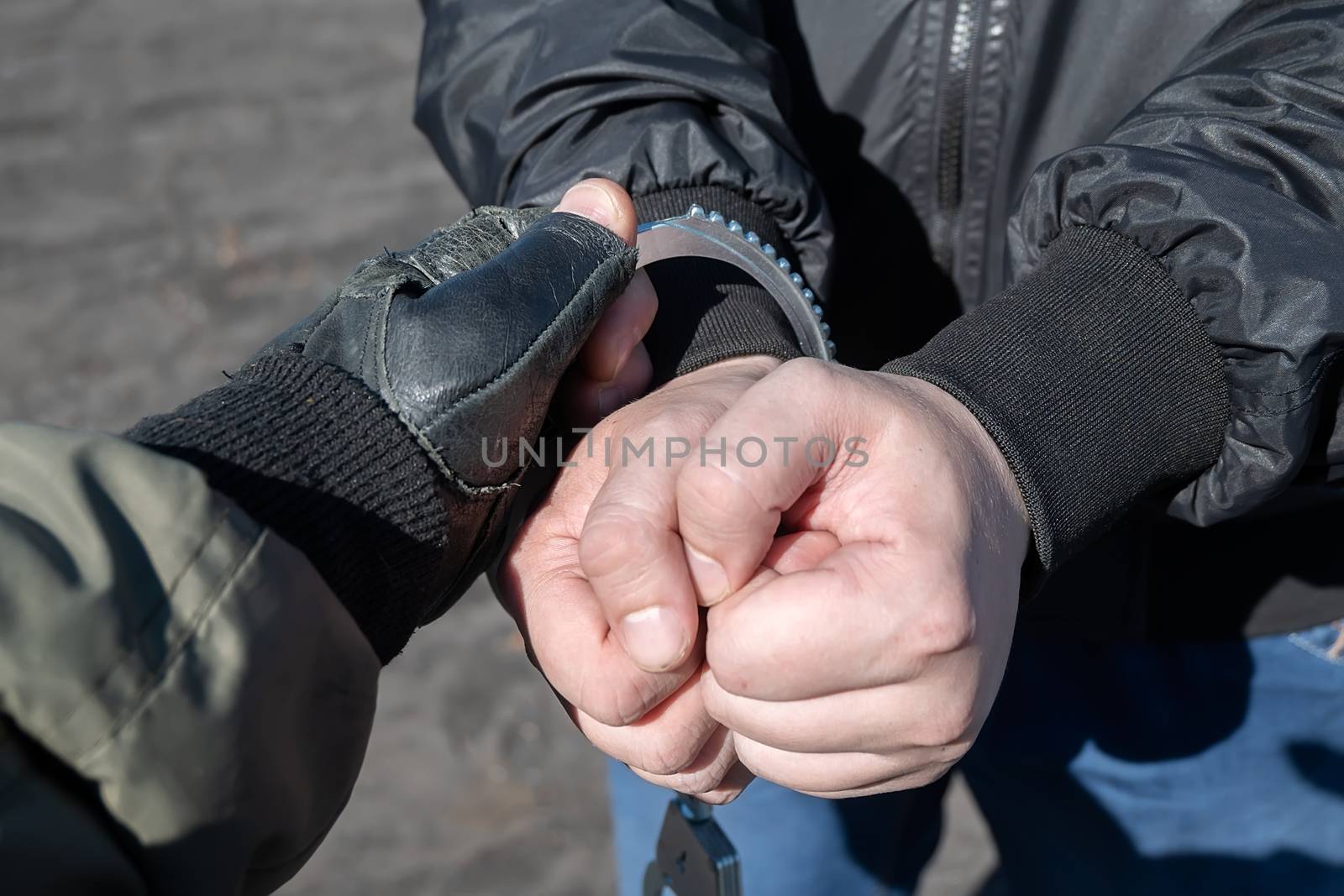 arrest of a criminal, a police officer puts handcuffs on the hands of a bandit by jk3030