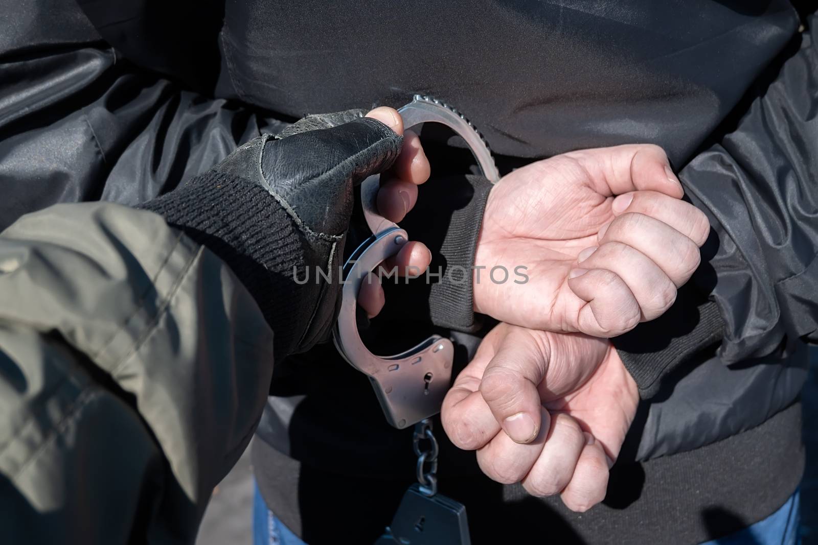 arrest of a criminal, a police officer puts handcuffs on the hands of a bandit by jk3030