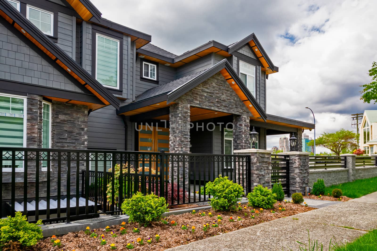 Luxury residential house with front behind metal fence. Big family house with landscaped front yard