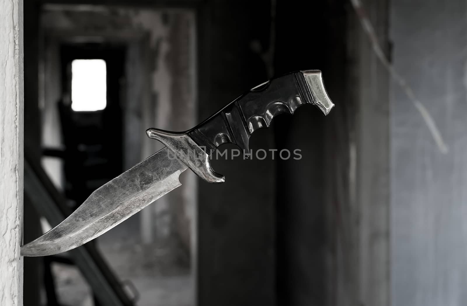 terrible fighting old knife stuck in the doorway on the background of the ruined corridor of the old abandoned house