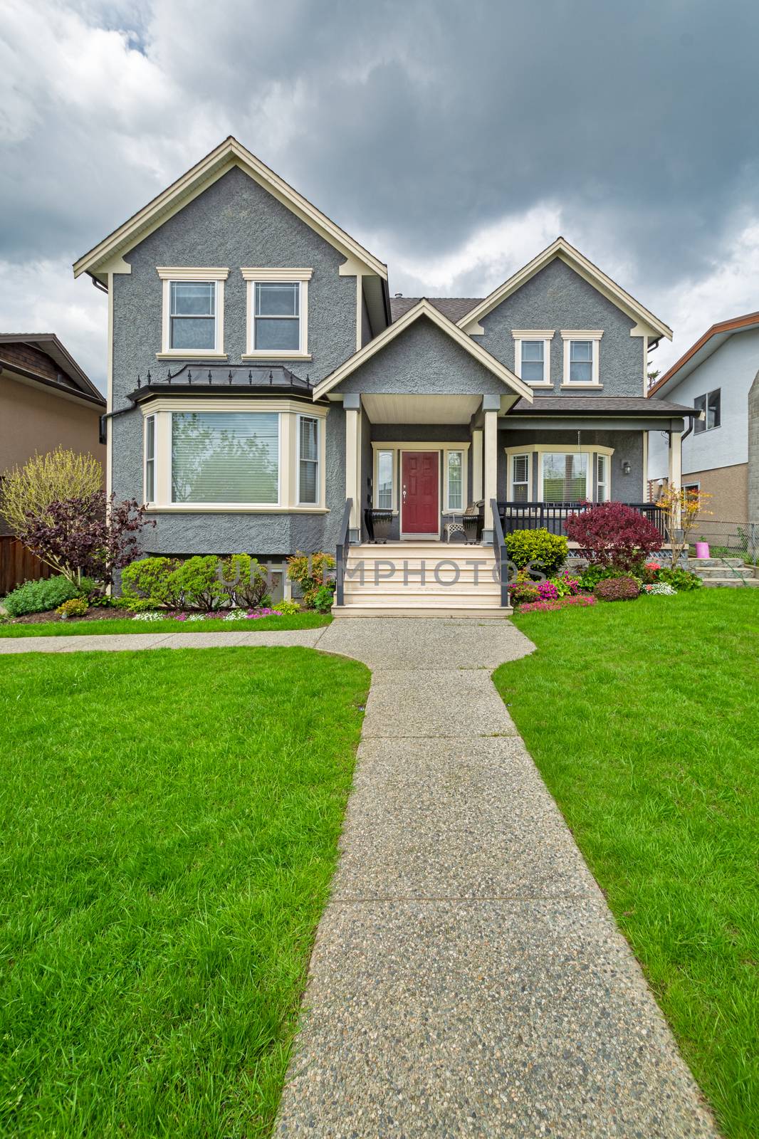 A perfect neighbourhood. Nice family house with curved concrete pathway over green lawn. Family house with chair under the porch