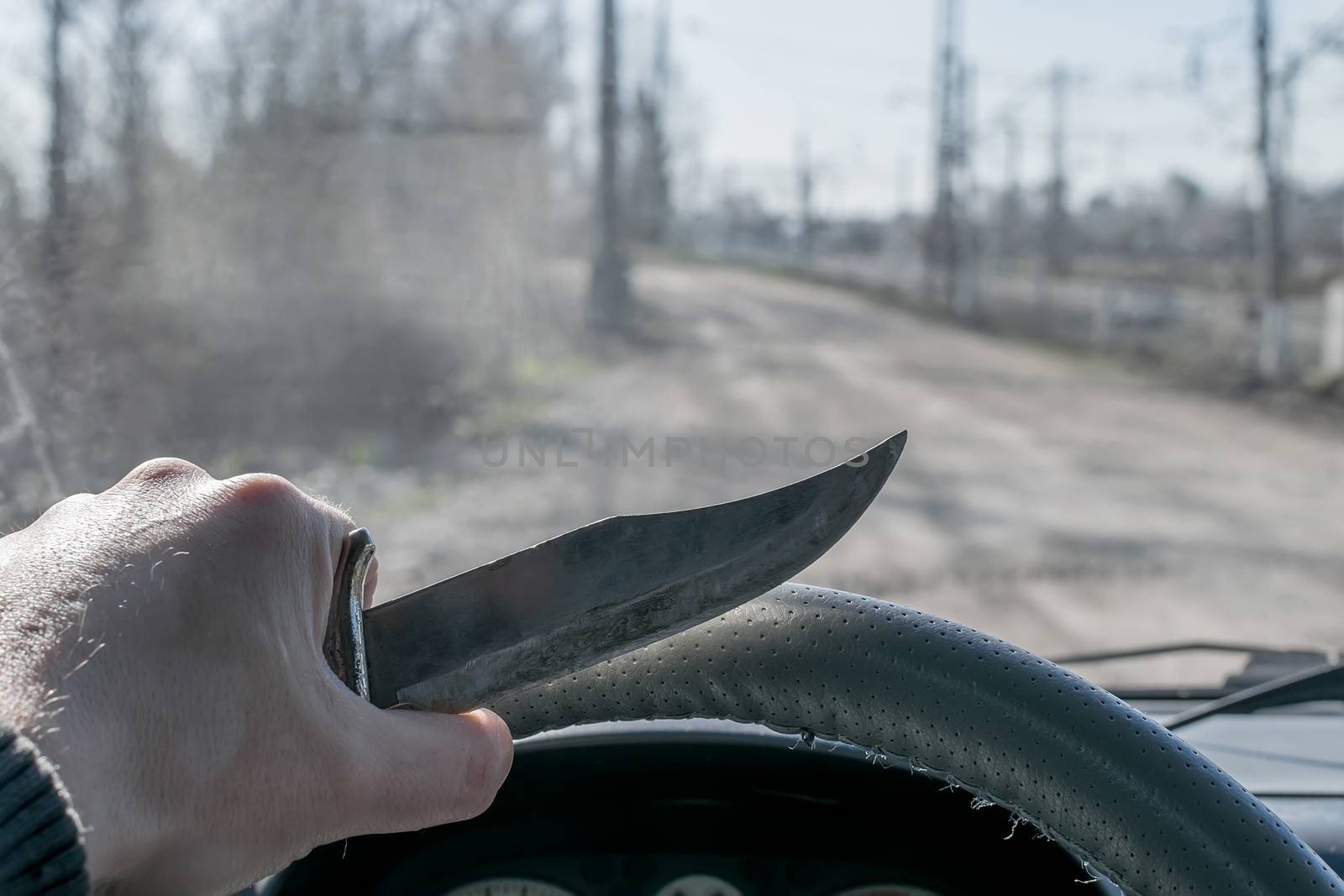 Crime, man, driving a car holding a knife, riding on the road