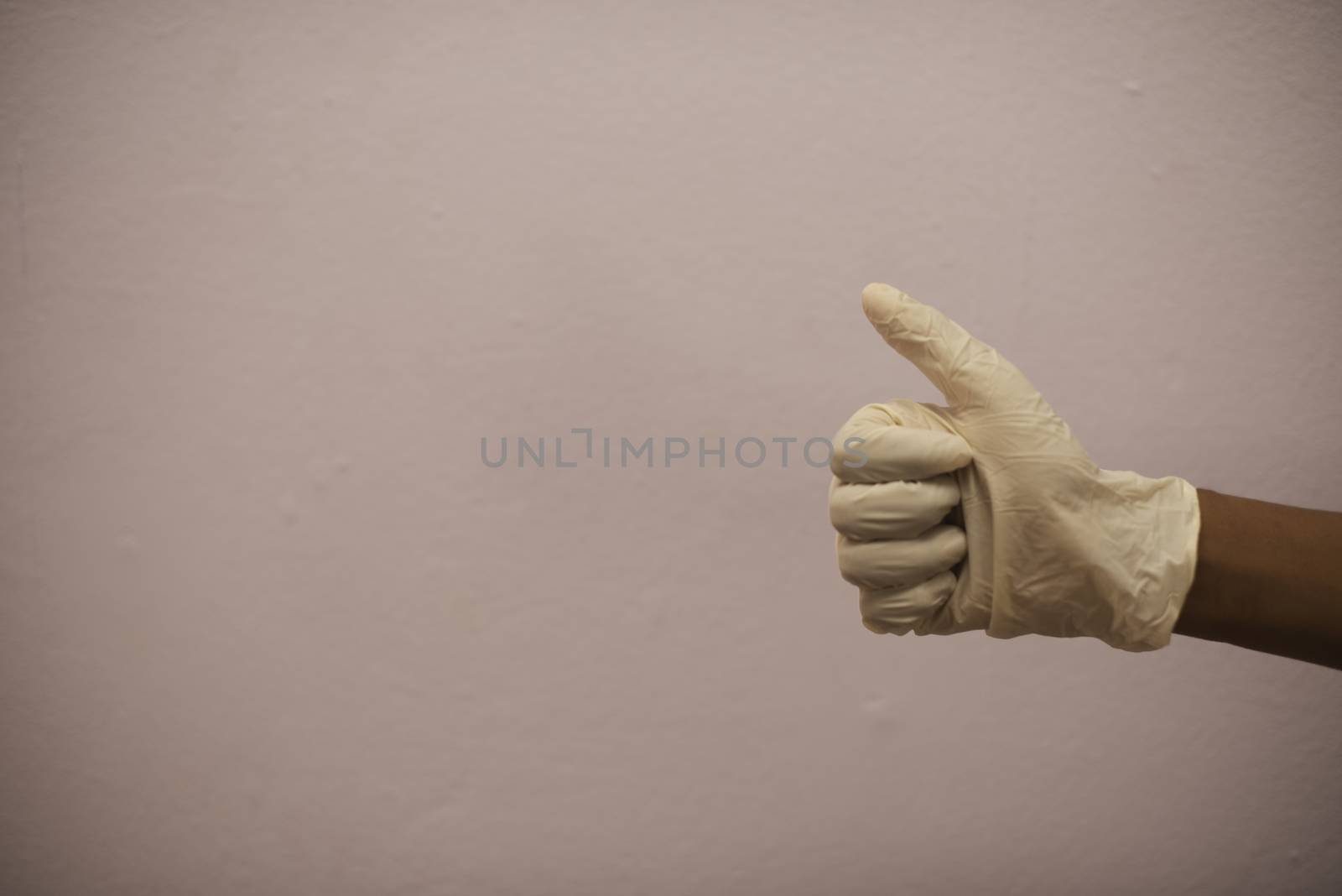 Hand with surgical glove showing thumbs up gesture