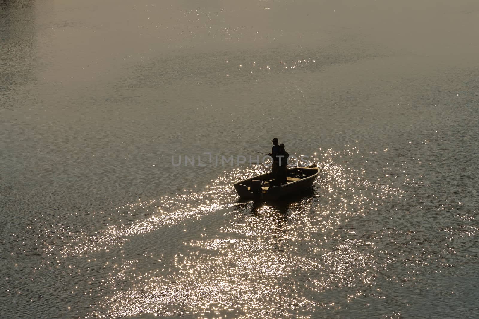 fishermen with fishing rods on a boat, sunset backlit shooting by VADIM