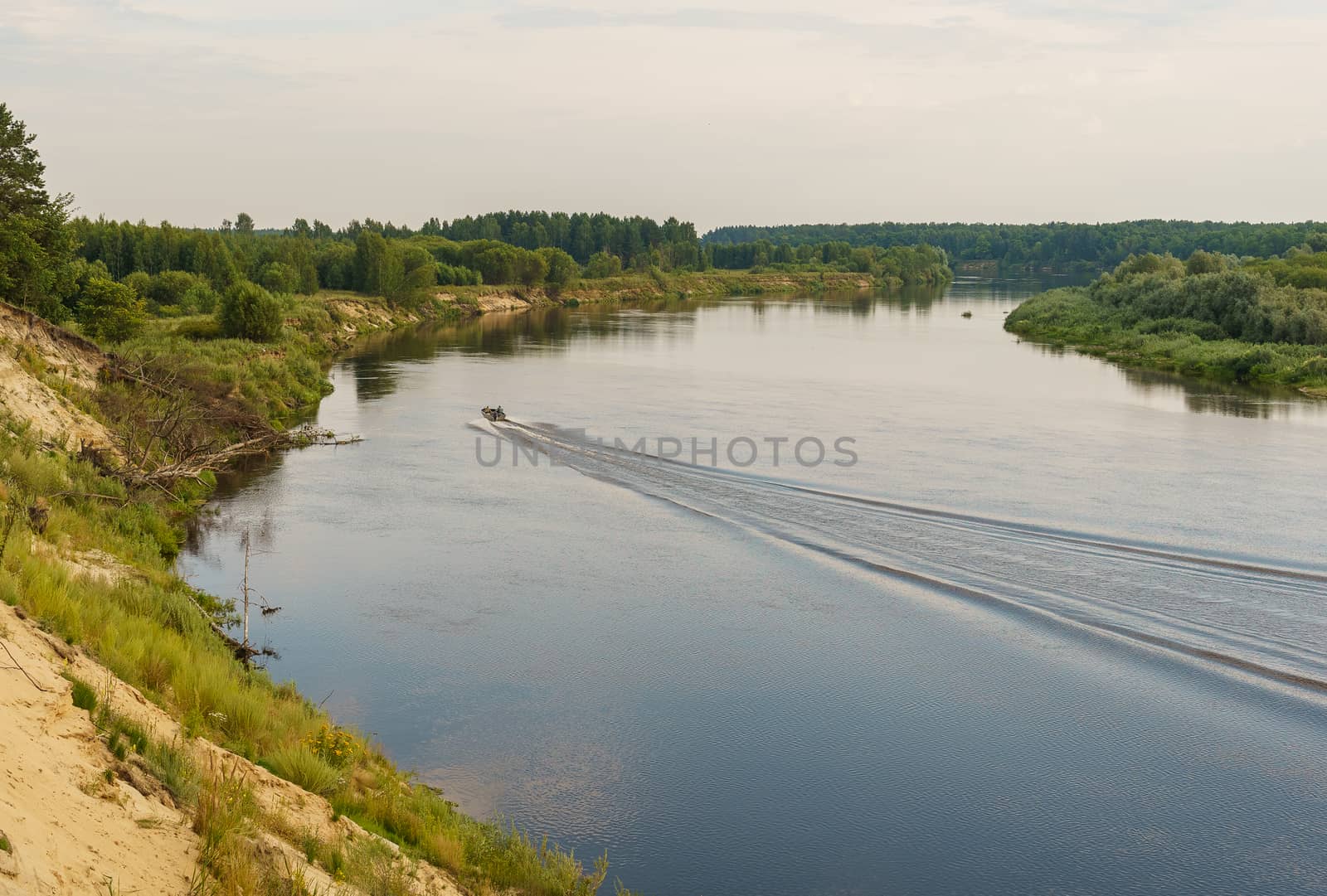 riverbank and a motor boat goes on the water, leaving a mark