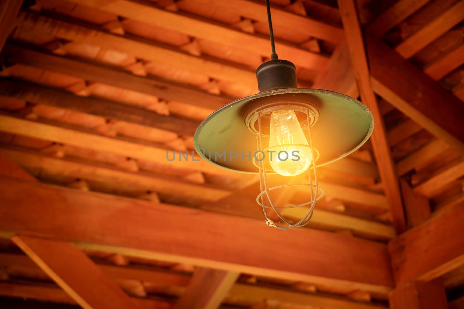 Incandescent light bulb hanging from ceiling over head from roof house gable corner at Asian countryside. Incandescent light bulb, old style and low technology. Edison lamp.