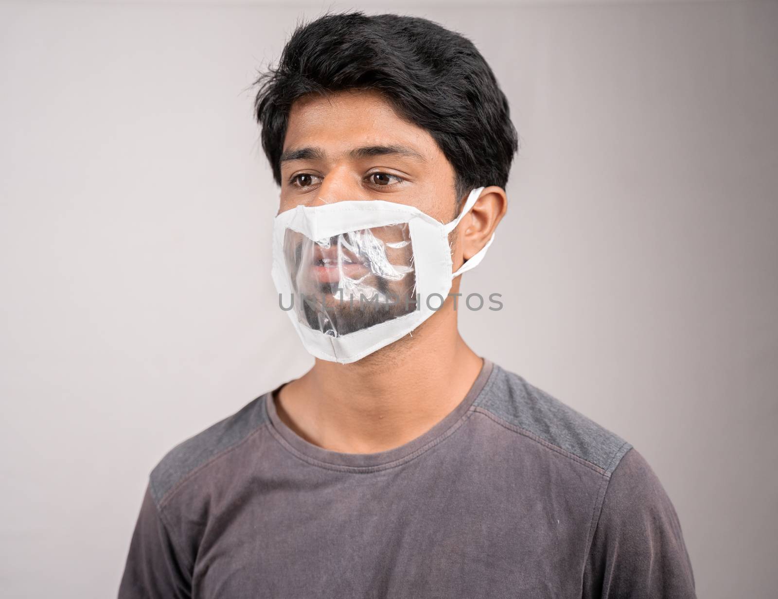 young man with transparent Medical face mask, to help hearing imperimeant or deaf people to understand lipreading during coronavirus or covid-19 outbreak by lakshmiprasad.maski@gmai.com