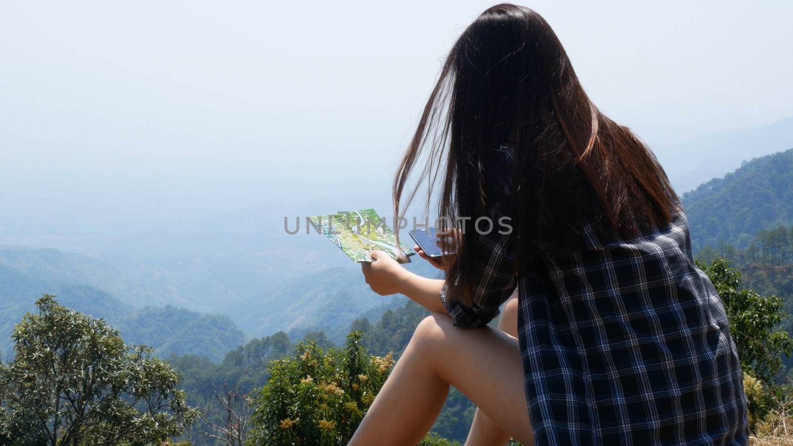Technology with application on mobile phone. Asian tourist woman use application touching screen on smartphone mobile and map for search tour and travel information with nature view at background. by asiandelight