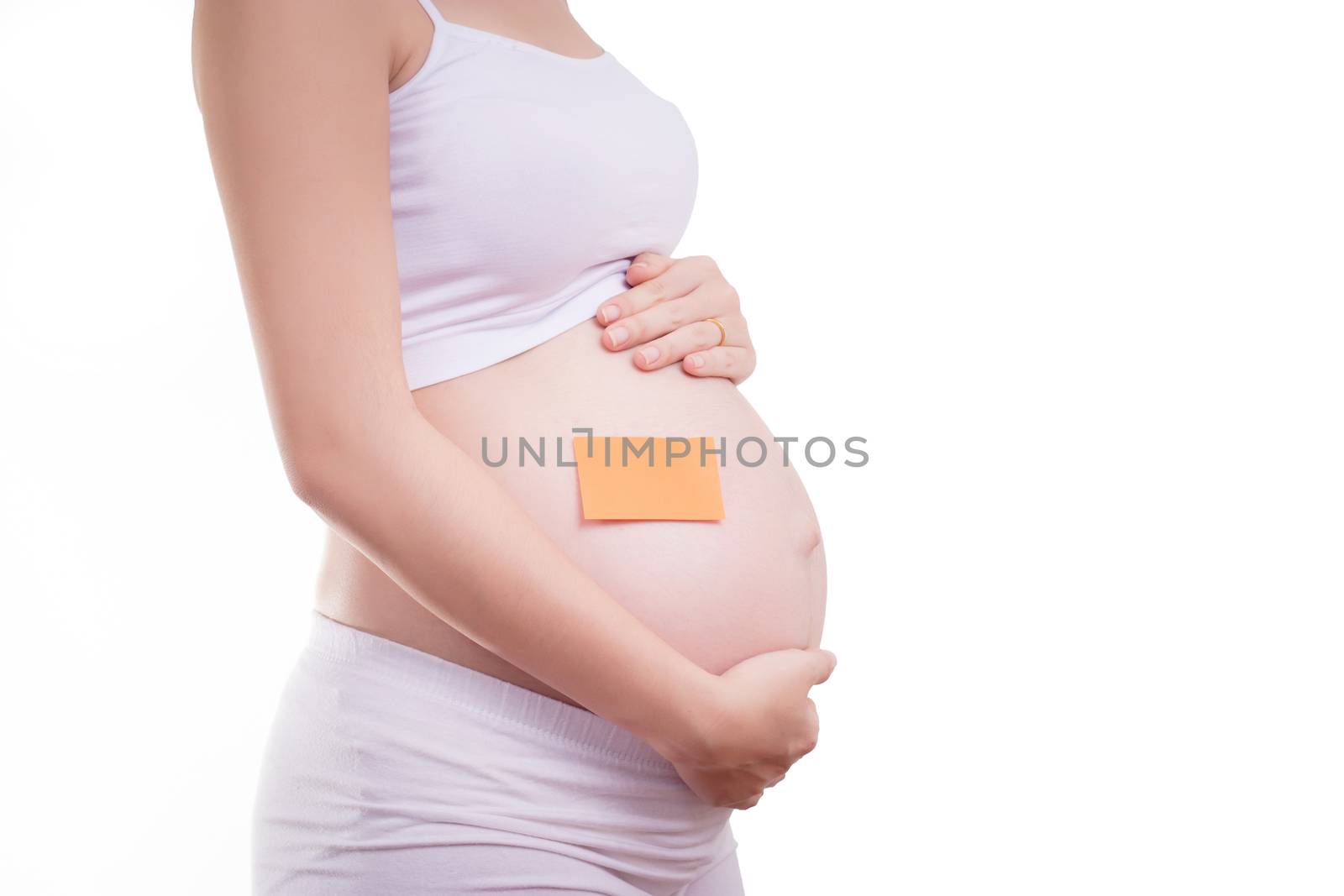 Pregnant woman with blank stick notepad on her belly, anonymous face. Beautiful Asia female model in her 20s. Pregnant woman isolated on white background
