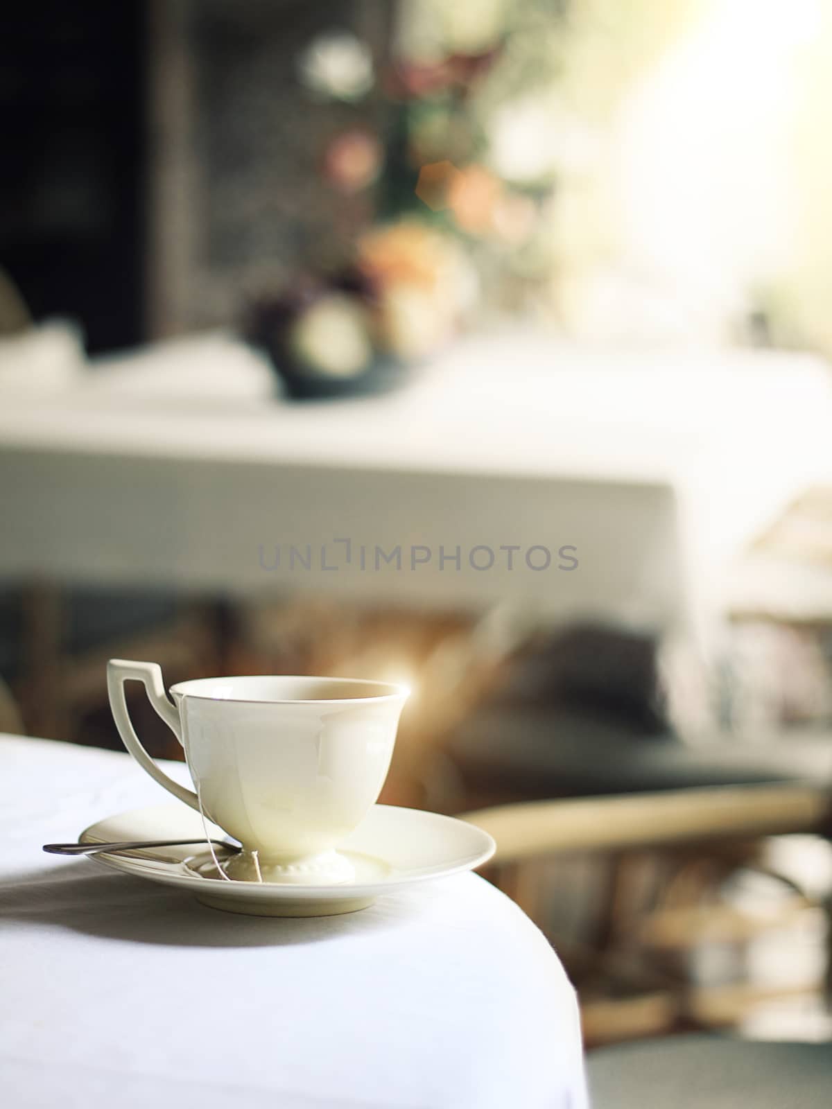 cup of hot steam coffee on table in cafe with morning glistening light reflect